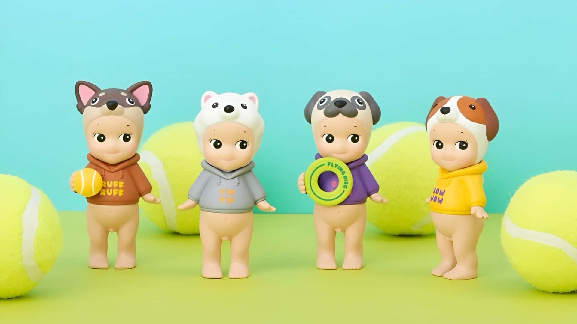  壁紙 — 四個可愛的狗主題玩具公仔穿著連帽衫，站在超大的網球之間，背景是青綠色。