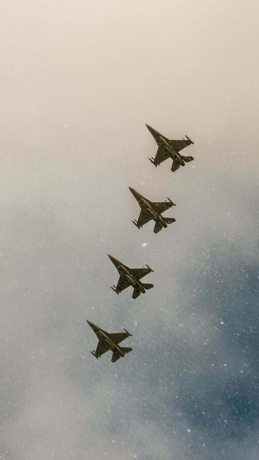  壁紙 — 四架戰鬥機在雲層密佈的天空中以緊密編隊翱翔，帶有柔和藍色和灰色色調。