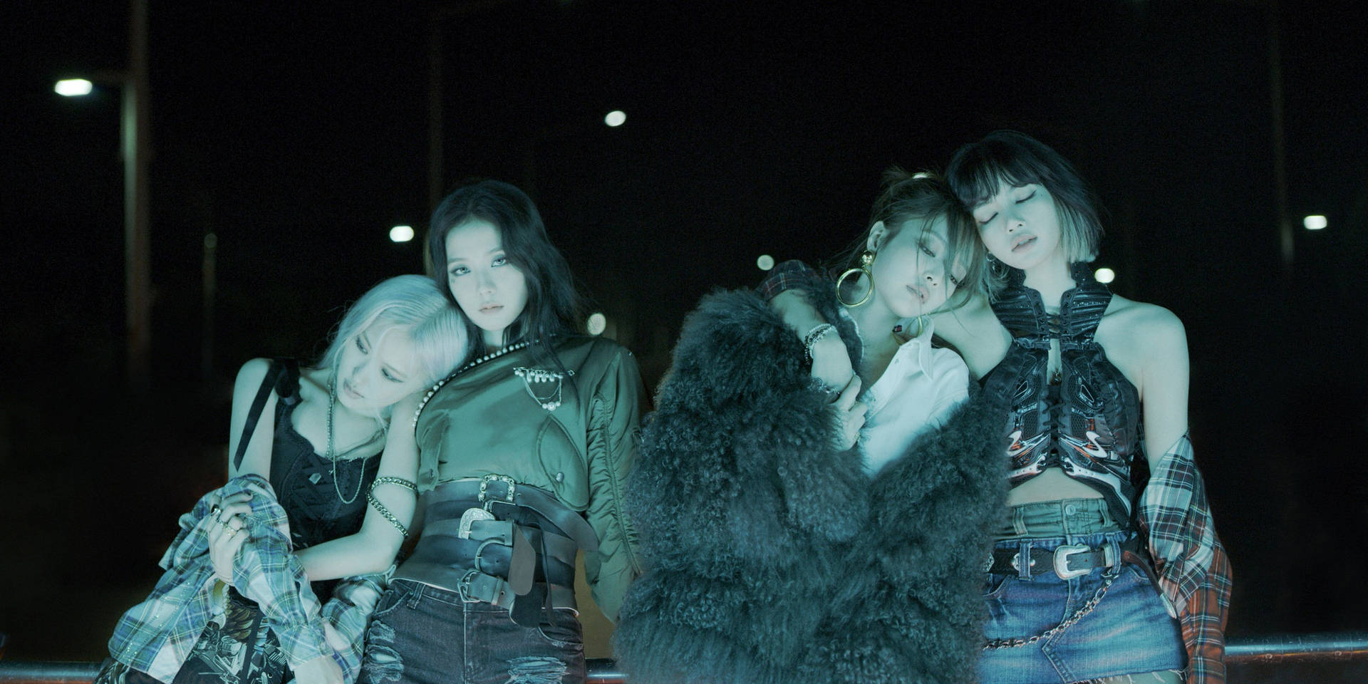 四位穿著龐克時尚的女性在夜晚的霓虹燈下一起擺姿勢。 — Blackpink 壁紙