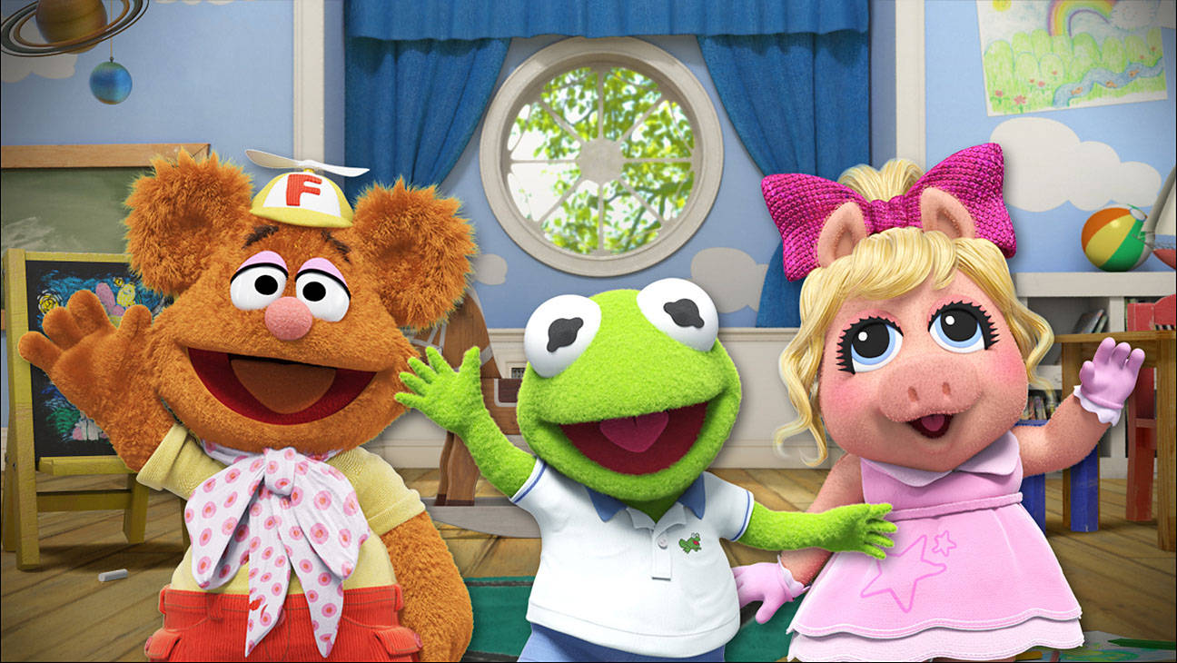 babies 桌布 壁紙 — Fozzie、Kermit 和 Miss Piggy 在一個有藍色牆壁和圓窗的色彩繽紛 Muppet 遊戲室裡開心地揮手。