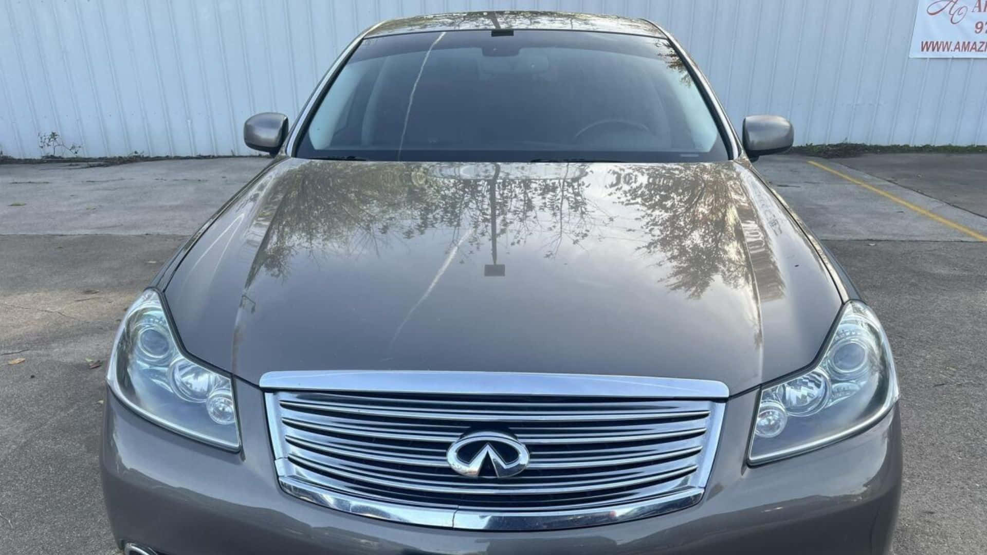 Infiniti M35 桌布 壁紙 — 一輛時尚灰色Infiniti轎車停放在戶外的正面視圖，引擎蓋上反射著樹木的倒影。