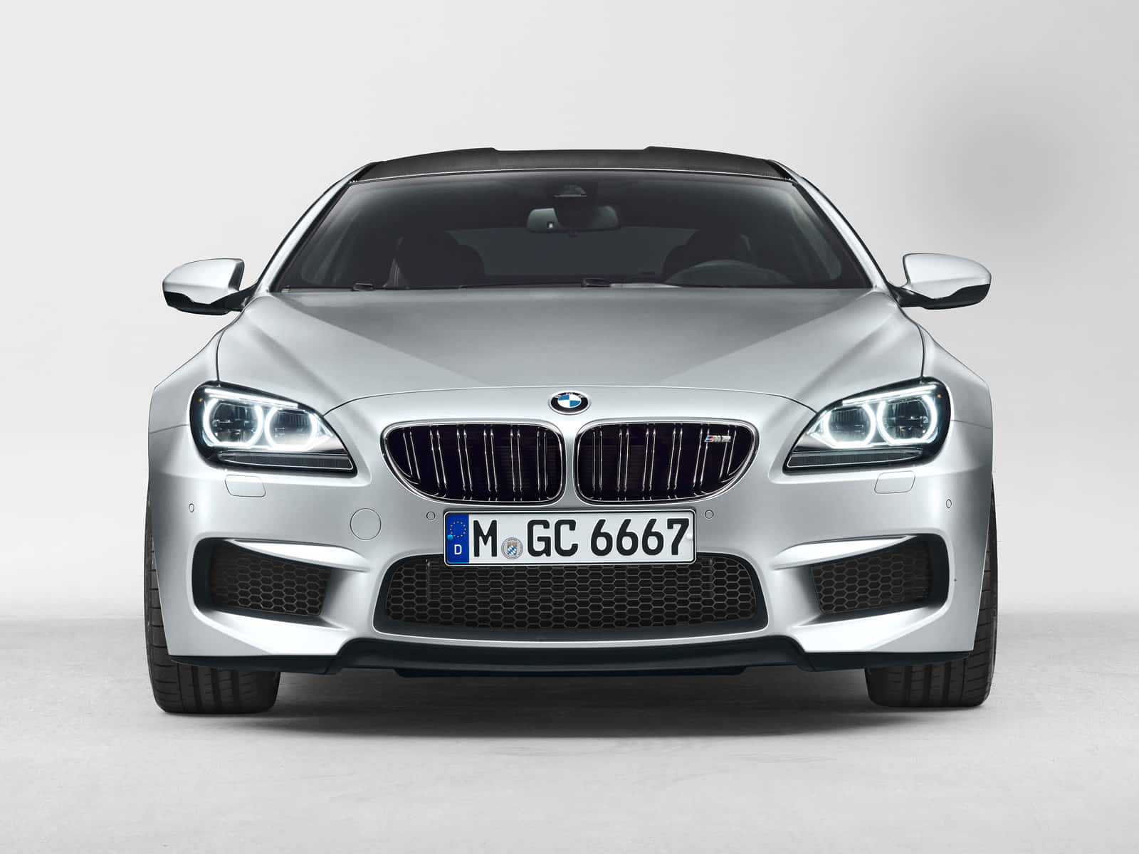 Bmw M6 桌布 壁紙 — 時尚銀色寶馬6系列轎跑車的前視圖，帶有發光頭燈，背景為簡約白色工作室。
