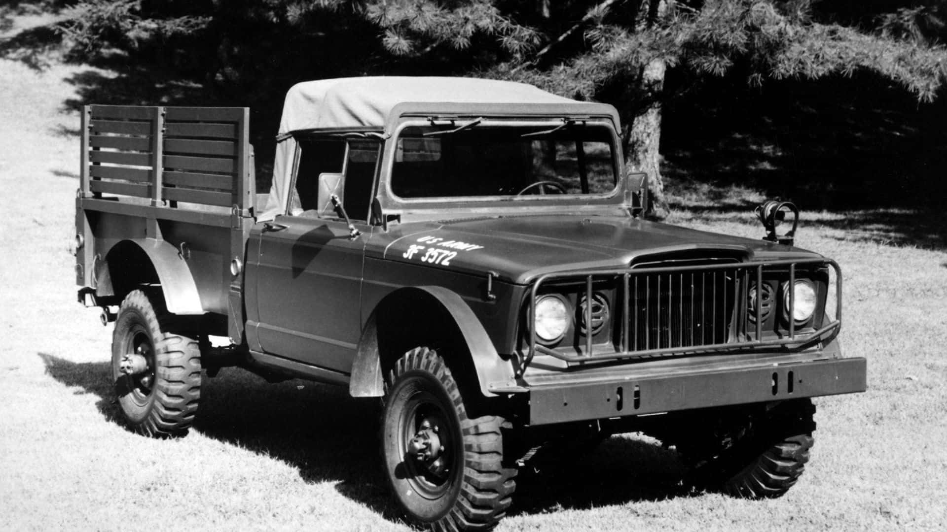 Jeep Gladiator 桌布 壁紙 — 一輛復古軍用卡車，帶帆布頂篷和木條車廂，以黑白風格停放在樹下的草地上。