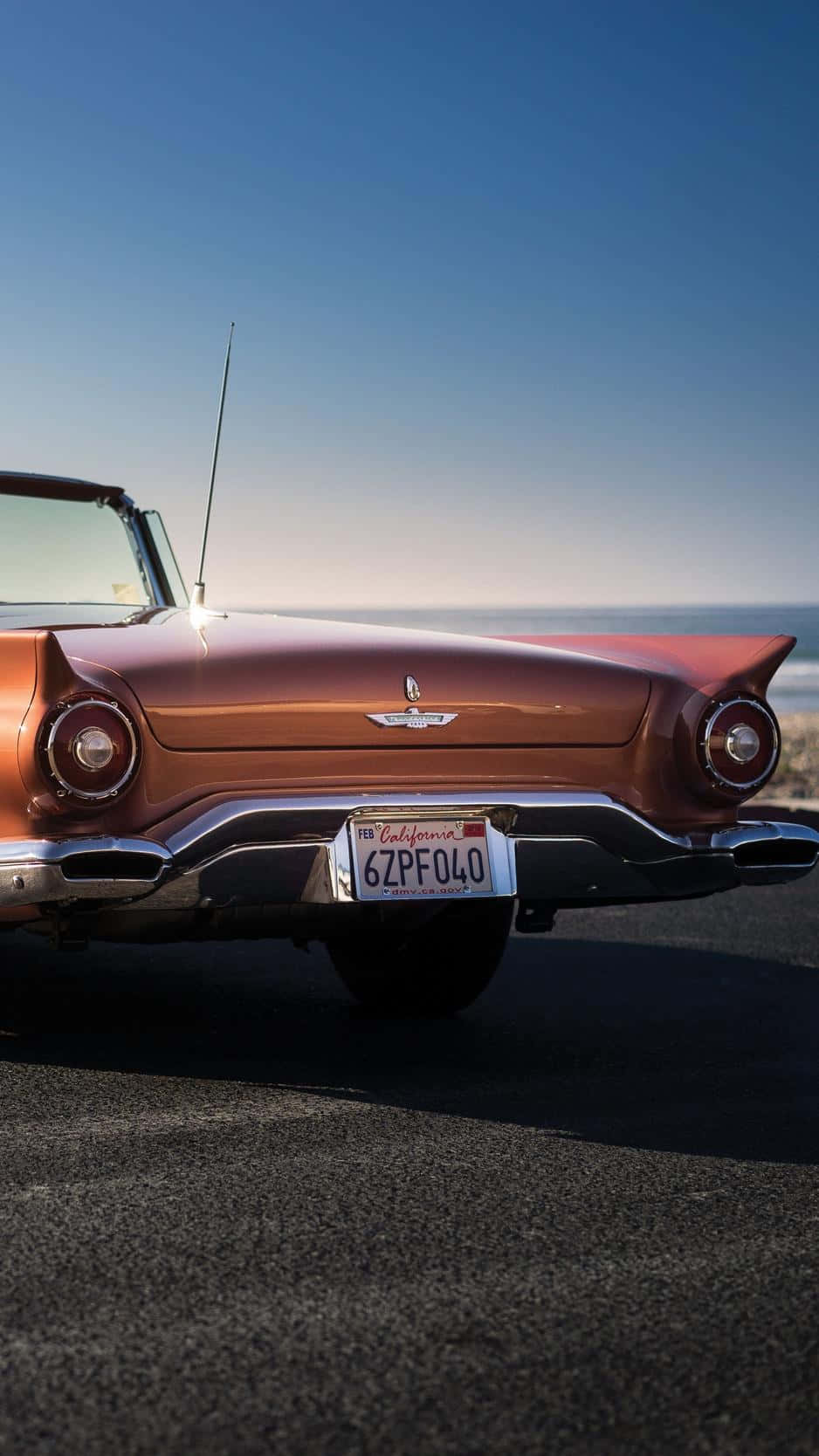 Ford Thunderbird 桌布 壁紙 — 一輛復古銅色敞篷車停泊在海岸柏油路上，天空清澈湛藍，海平線一望無際。