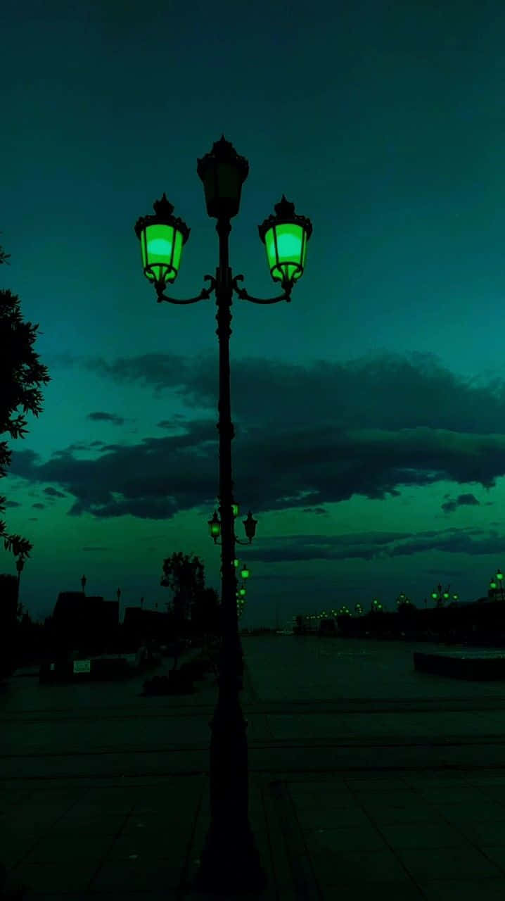  壁紙 — 一盞復古路燈，帶有發光的綠色燈籠，在陰沉、烏雲密布的暮色天空下高高聳立。