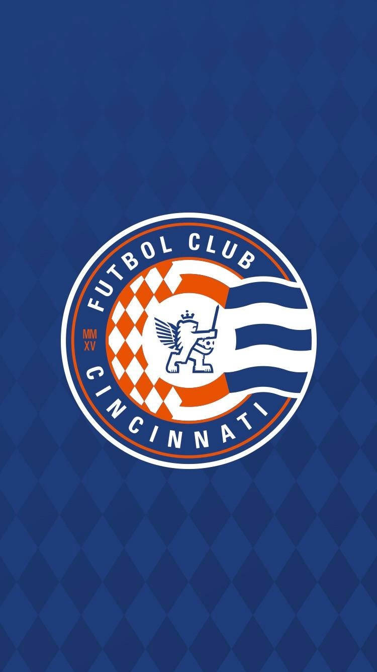 足球 桌布 壁紙 — Futbol Club Cincinnati 標誌居中於藍色菱形圖案背景上。
