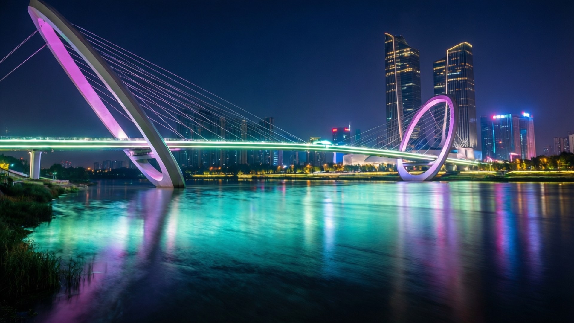 Nanjing Eye at Night 壁紙 — 一條未來風格的粉紅色和綠色燈光纜橋橫跨一條河流，反射著霓虹城市燈光，襯托著黑暗的夜空。