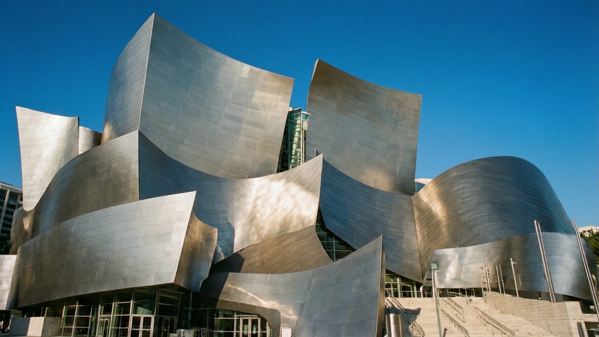 Disney Hall Steel Curves 壁紙 — 一座未來風格的銀色建築，帶有流動的金屬曲線，矗立在清澈的藍天下。