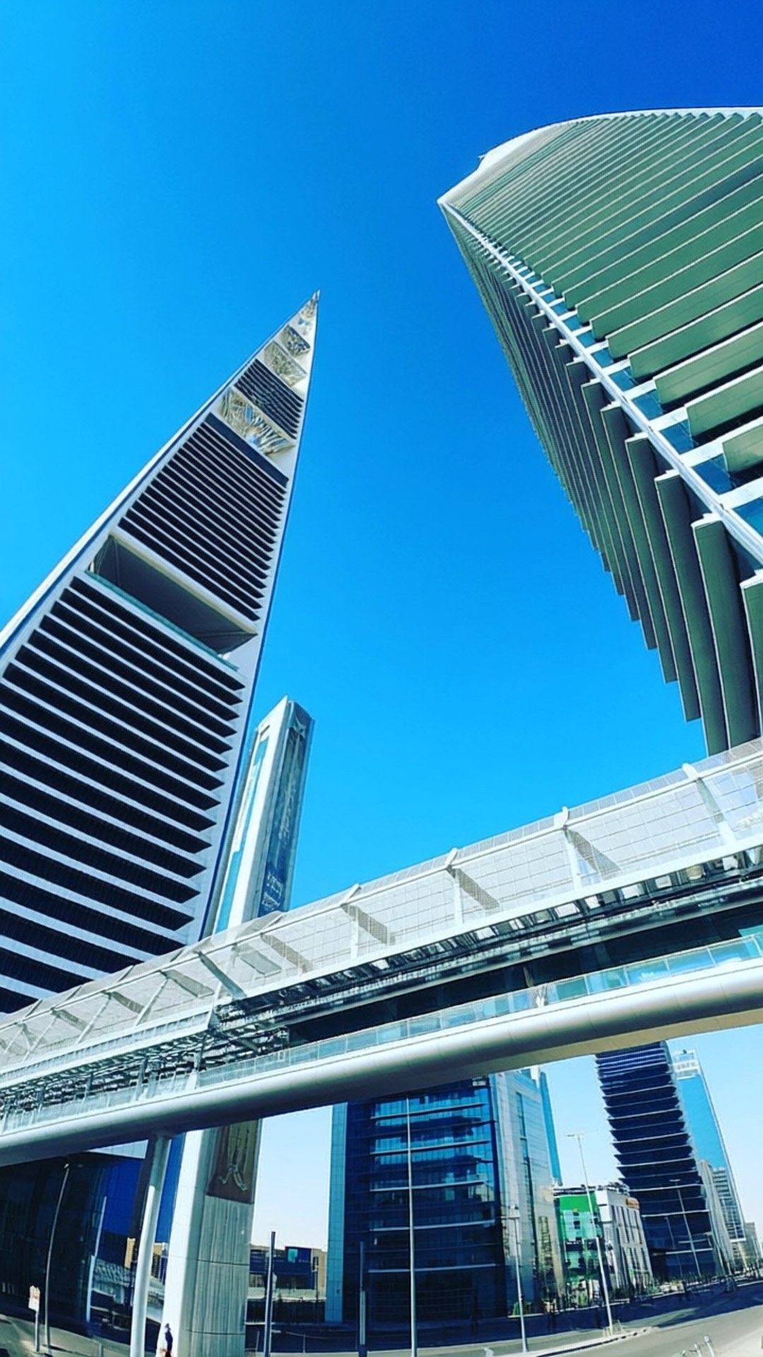 KAFD Modern Skyline 壁紙 — 低角度拍攝兩座未來主義摩天大樓，玻璃和鋼結構外牆襯托著清澈的藍天。