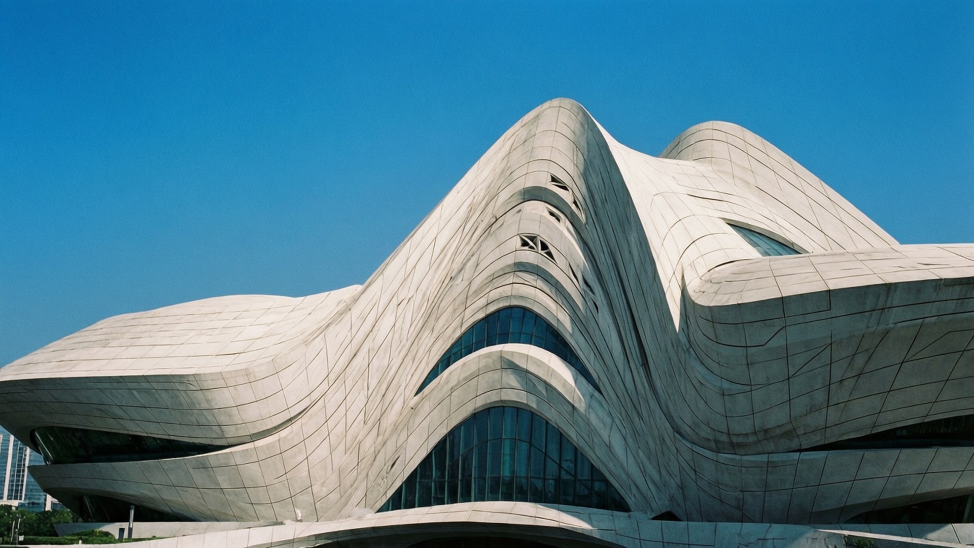 Modern Art Museum 壁紙 — 一座未來主義的白色混凝土建築，帶有流暢的曲線和玻璃窗，矗立在清澈的藍天下。