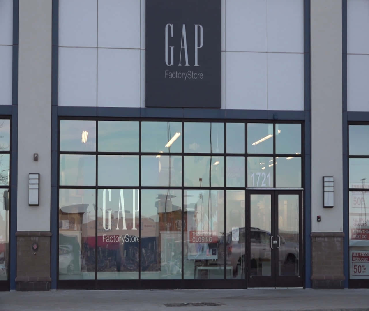 間隙 桌布 壁紙 — GAP Factory Store 的外牆，大型玻璃窗反射街燈，內部可見關閉標誌。