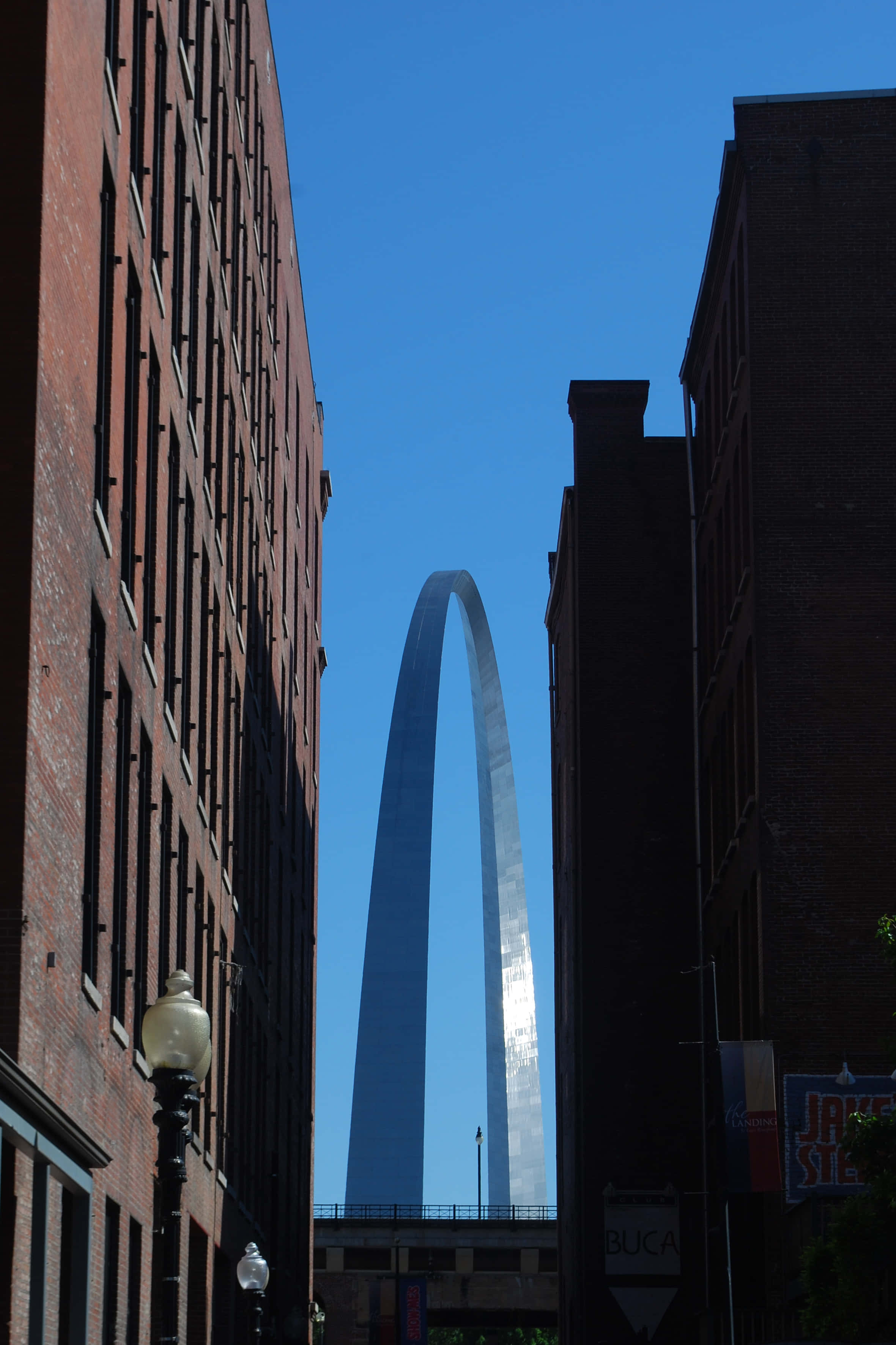 National Parks 桌布 壁紙 — Gateway Arch 在晴朗的藍天下，雄偉地矗立在兩座磚砌建築之間。