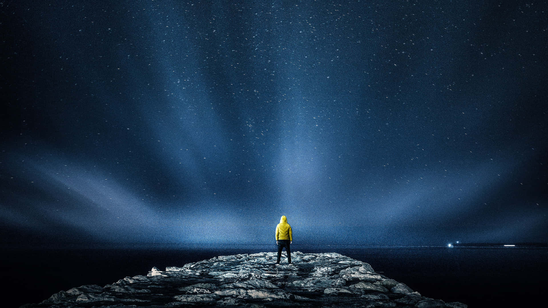 穿黃色外套的人站在懸崖上觀看極光和星星 — 藍色美學 壁紙