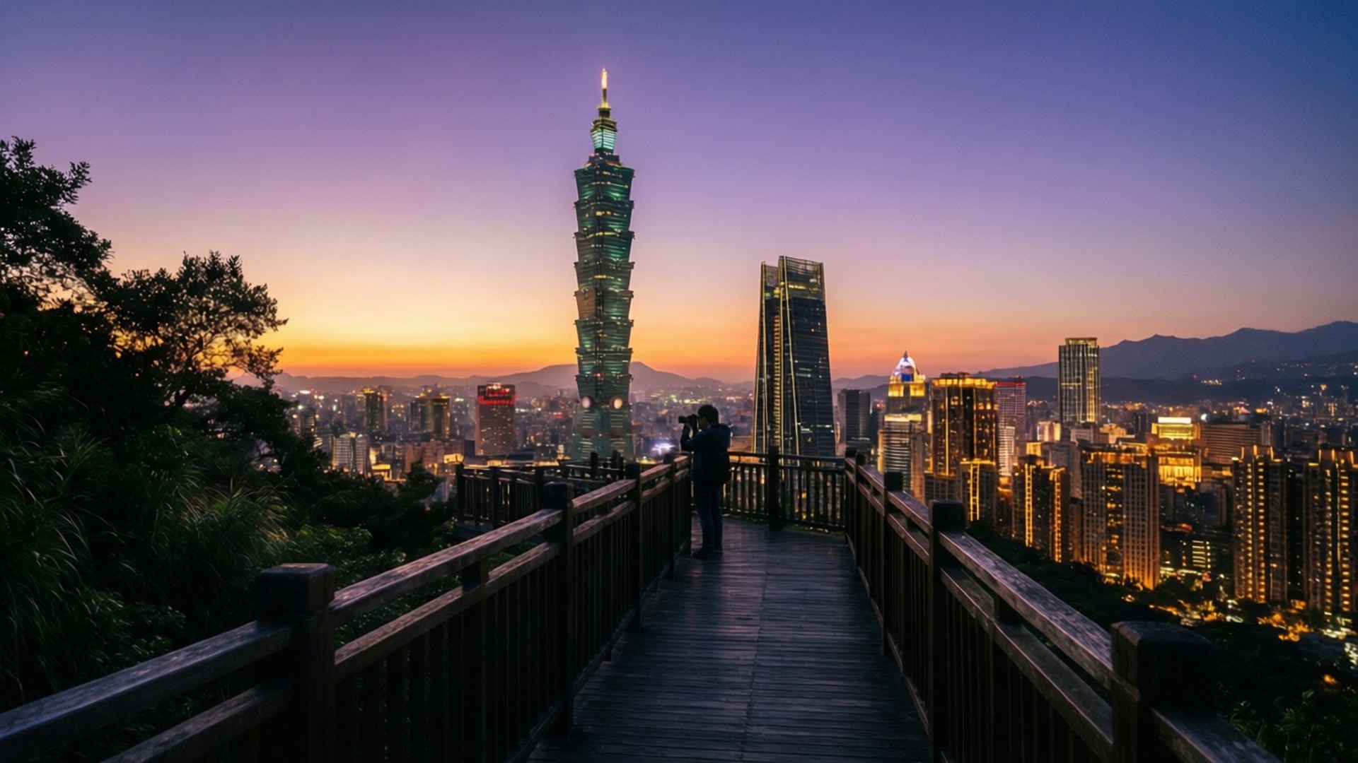人站在木製觀景台上拍攝日落時分的台北城市景觀，台北101亮起燈光 — 台灣 壁紙