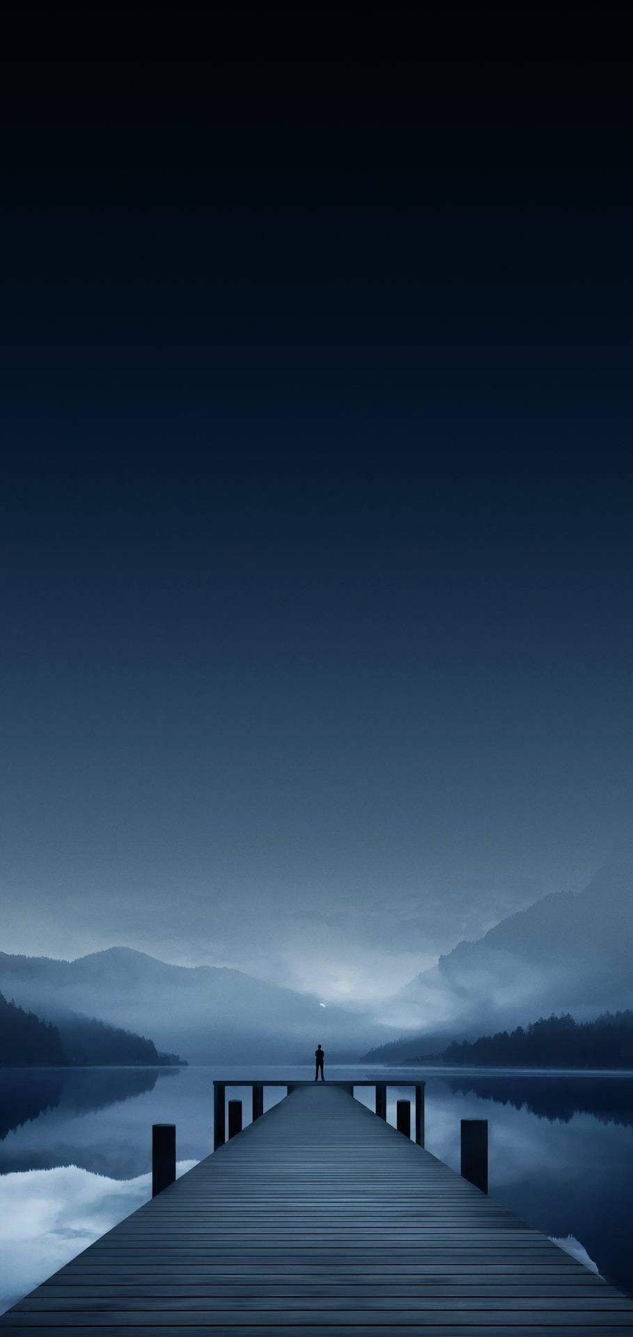 一個孤獨的人站在平靜湖泊上的木製碼頭盡頭，在暮色中。 — iPhone X 壁紙