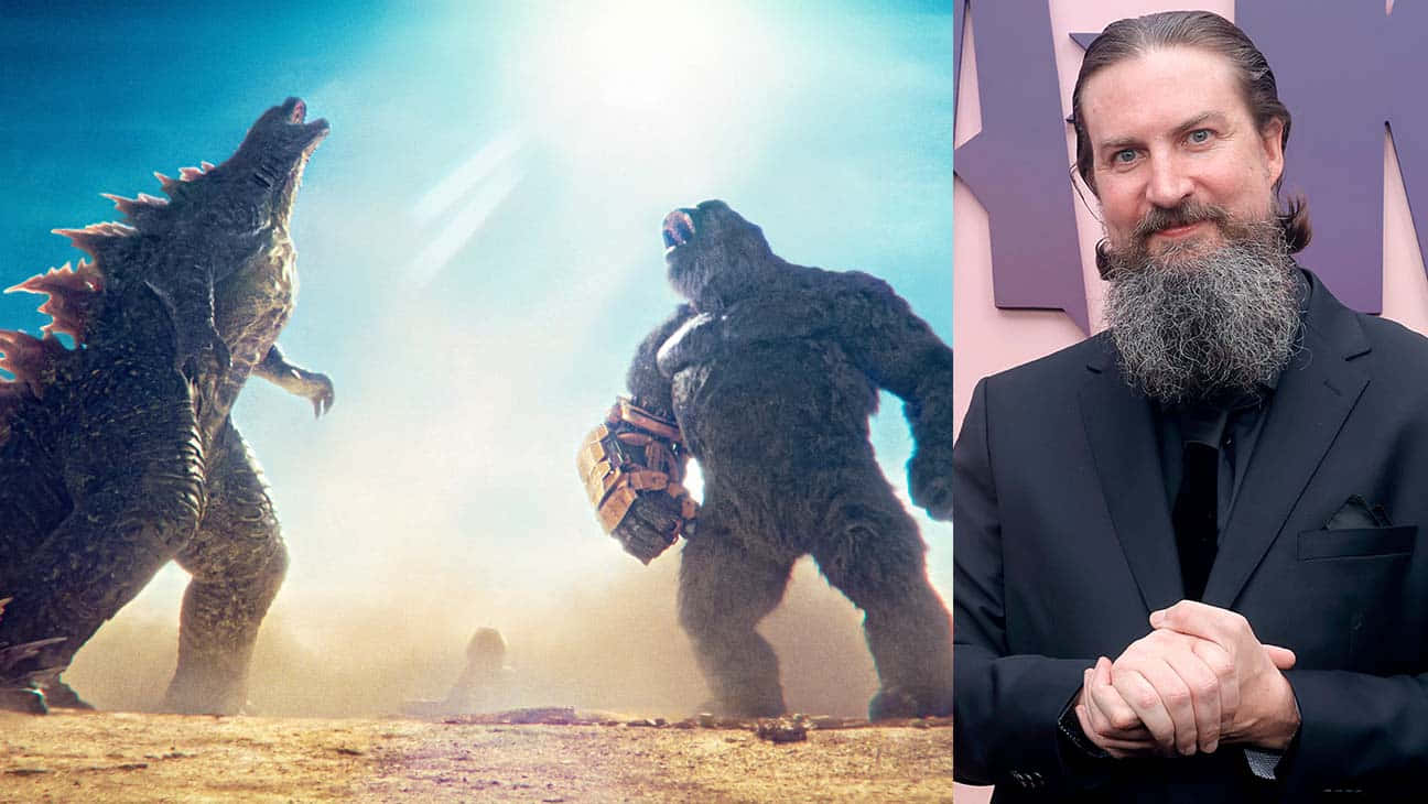 Godzilla X Kong The New Empire 桌布 壁紙 — 哥吉拉和金剛在明亮的陽光下進行史詩般的戰鬥，咆哮著，而一位留鬍鬚、身穿西裝的男子冷靜地站在一旁。