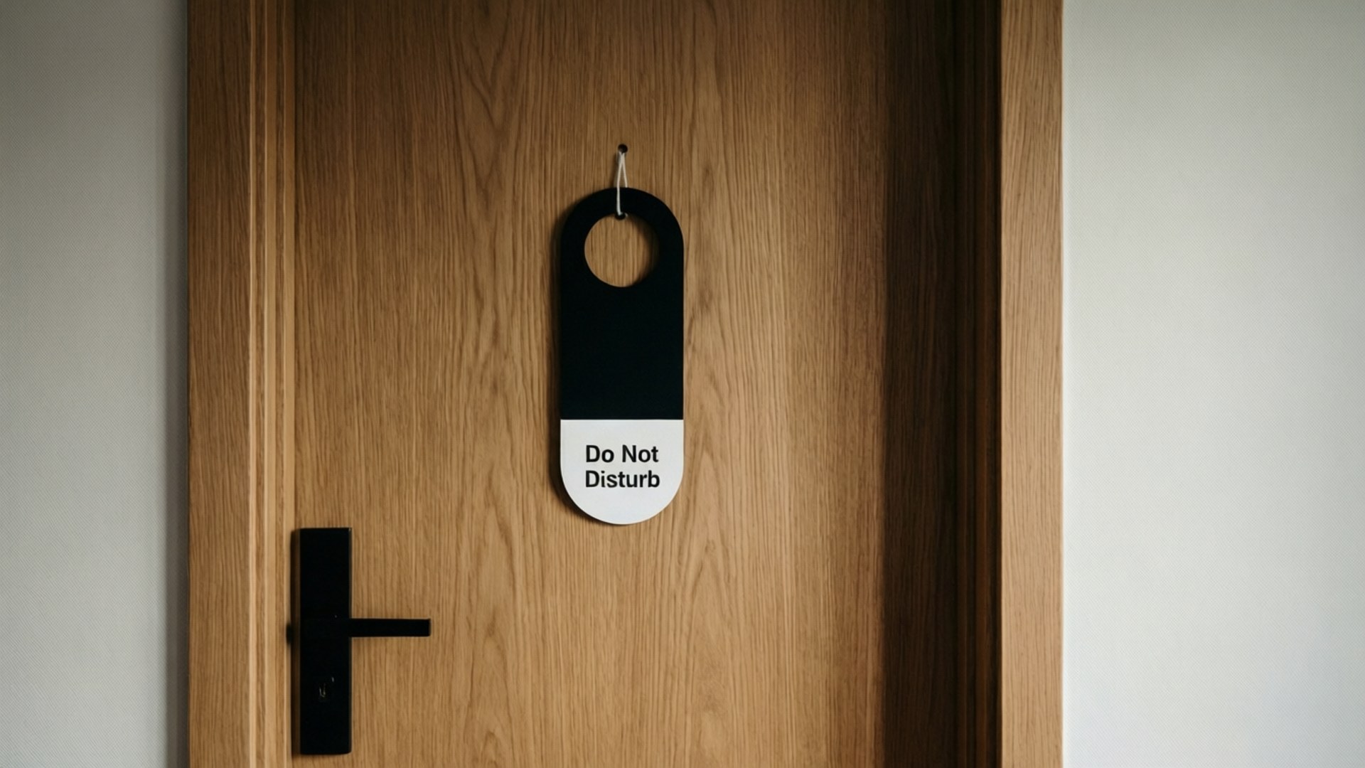 Do Not Disturb 桌布 壁紙 — 一個黑白的「請勿打擾」標誌掛在淺色木門上，門有現代黑色把手。