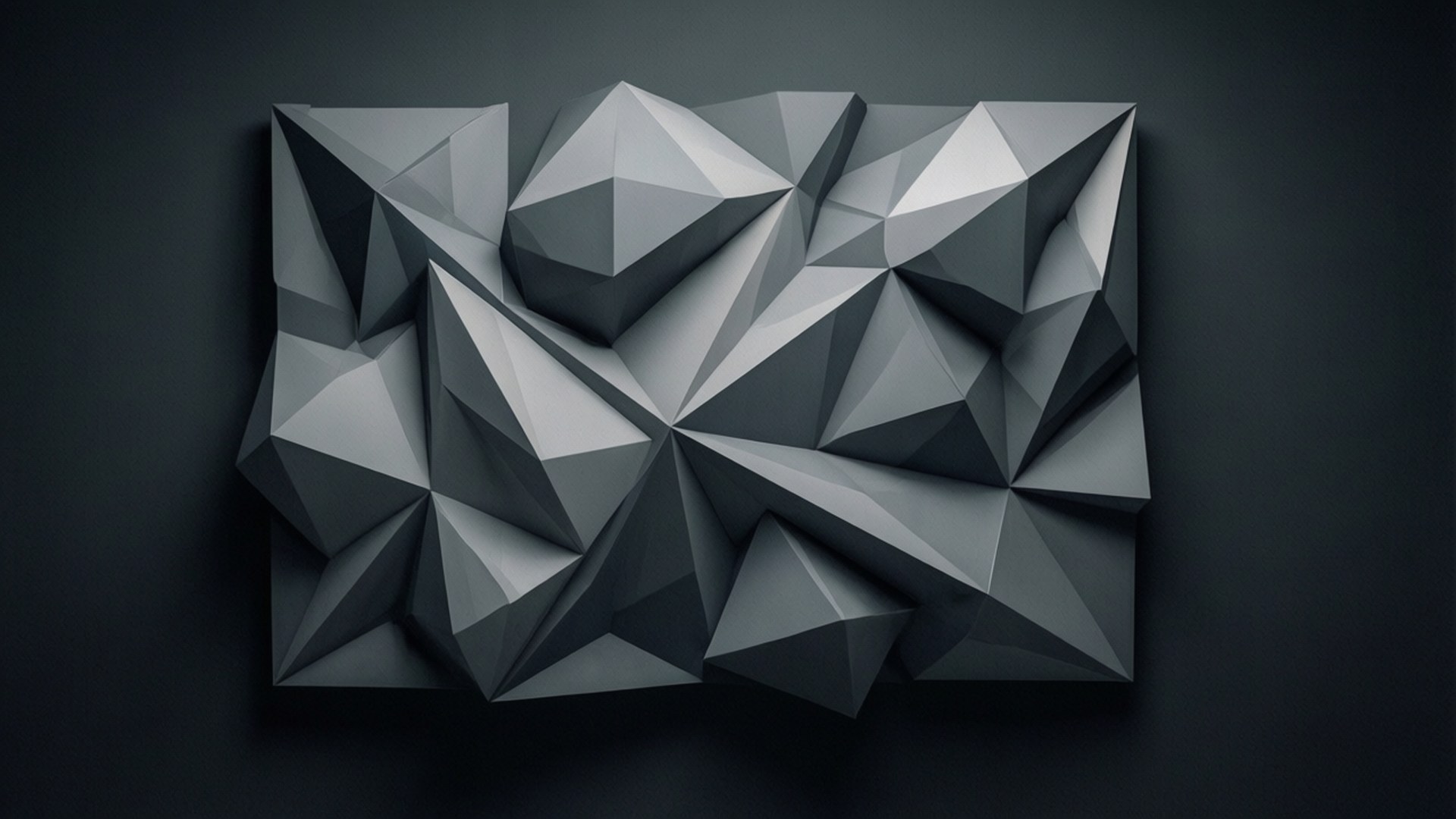 Grey Polygon Art 壁紙 — 一個幾何灰色抽象雕塑，具有尖銳的三角形切面，安裝在深色牆壁上。