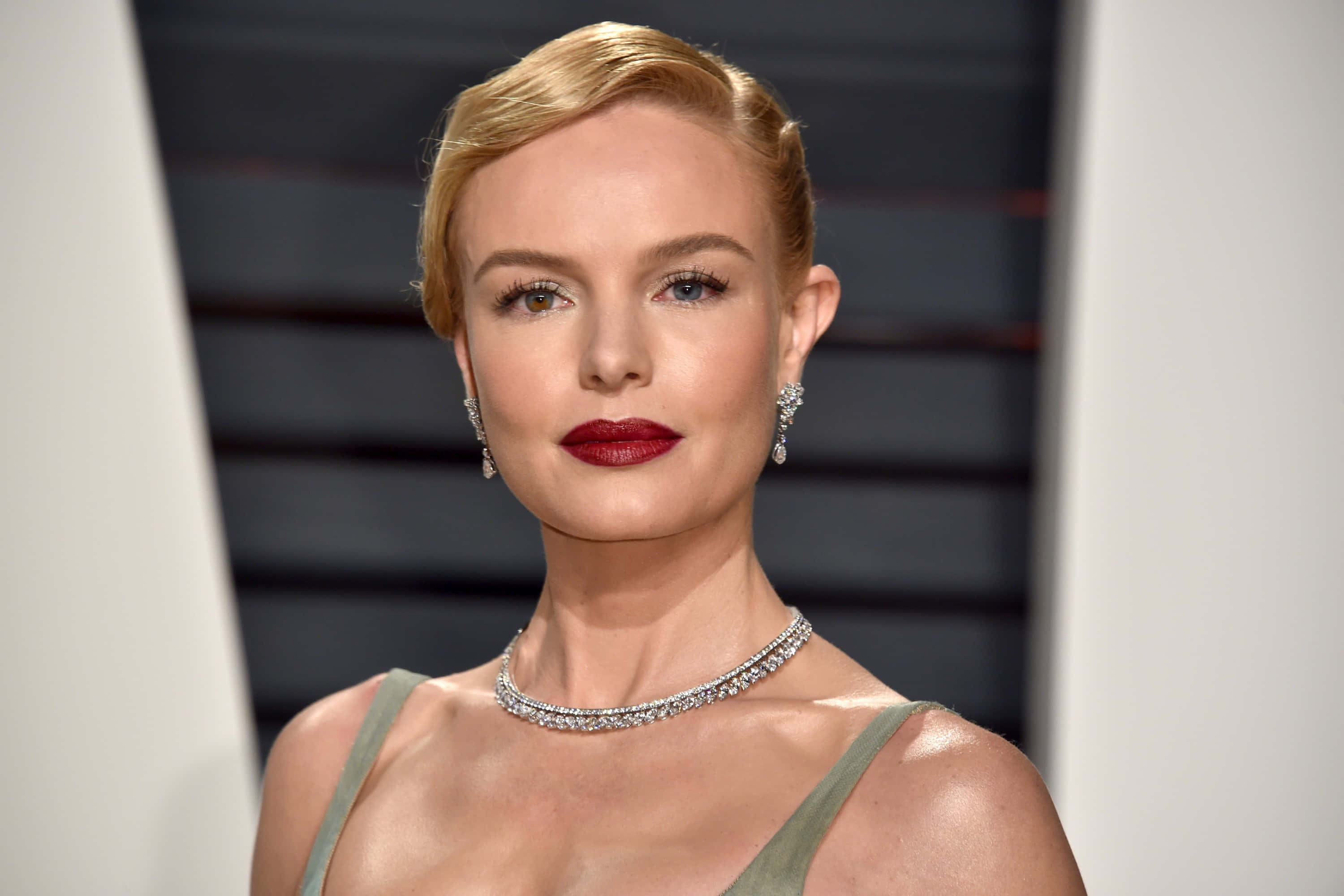 Kate Bosworth 桌布 壁紙 — 一位金髮碧眼、紅唇大膽的迷人女士，在深色條紋背景下佩戴閃閃發光的珠寶。