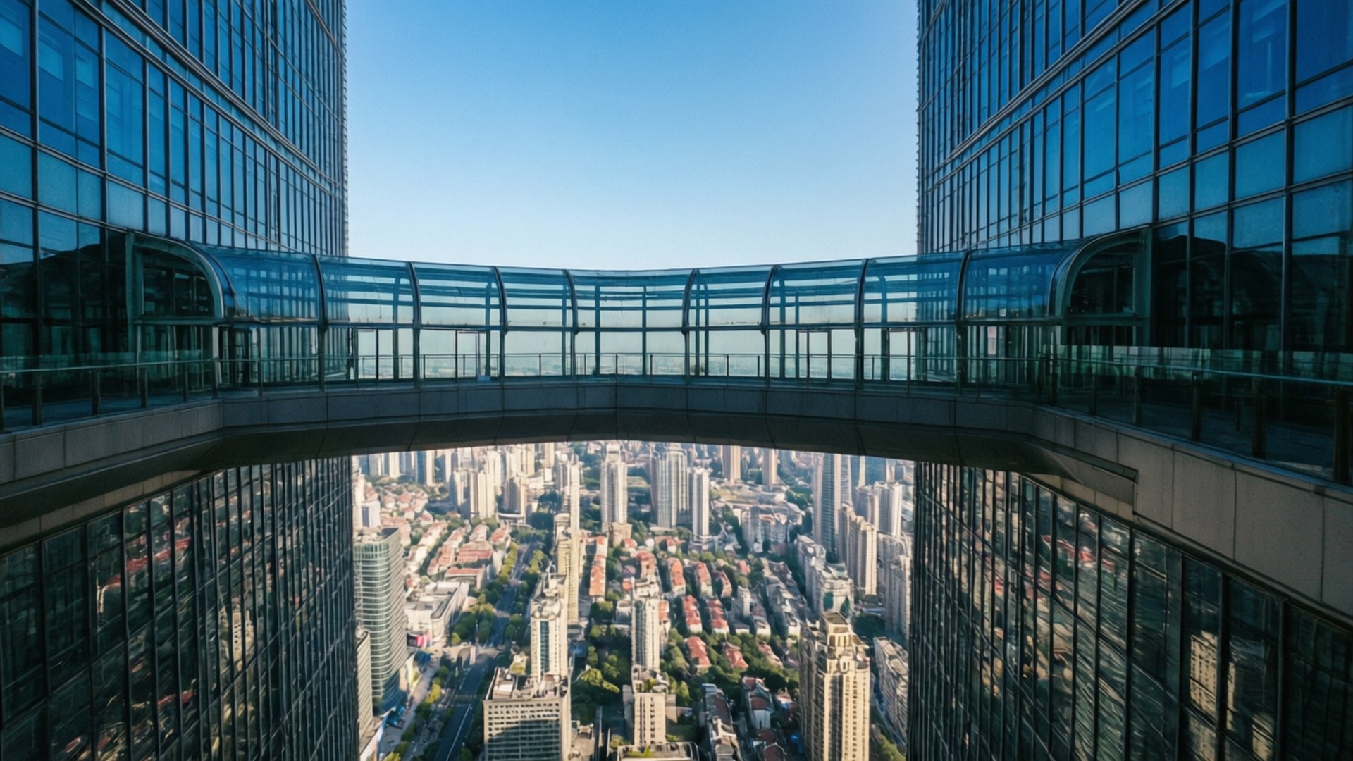 Skywalk Above Shanghai 壁紙 — 玻璃天空橋連接兩座高聳的摩天大樓，俯瞰著晴朗藍天下廣闊的城市峽谷。