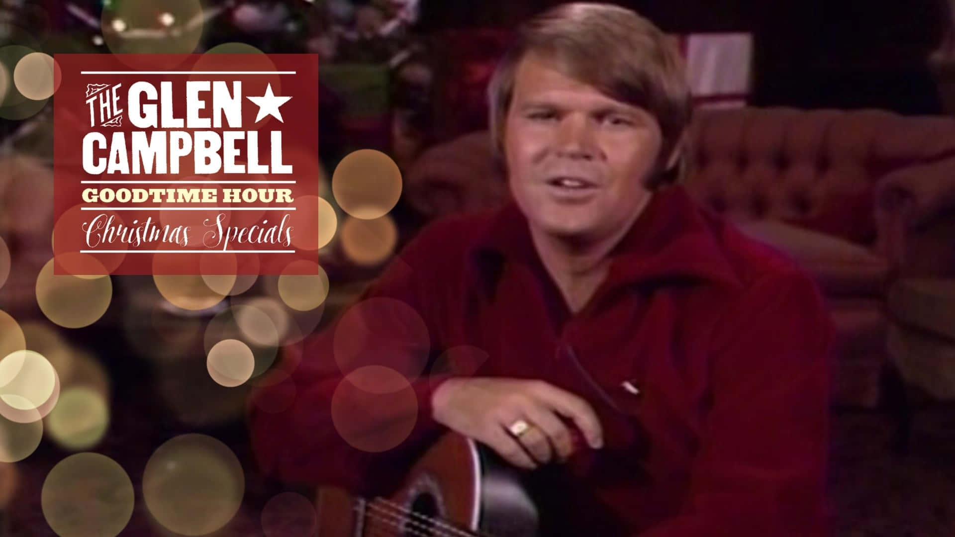  壁紙 — Glen Campbell 穿著紅色襯衫，手持吉他，背景有節日散景燈光和聖誕特輯標誌。