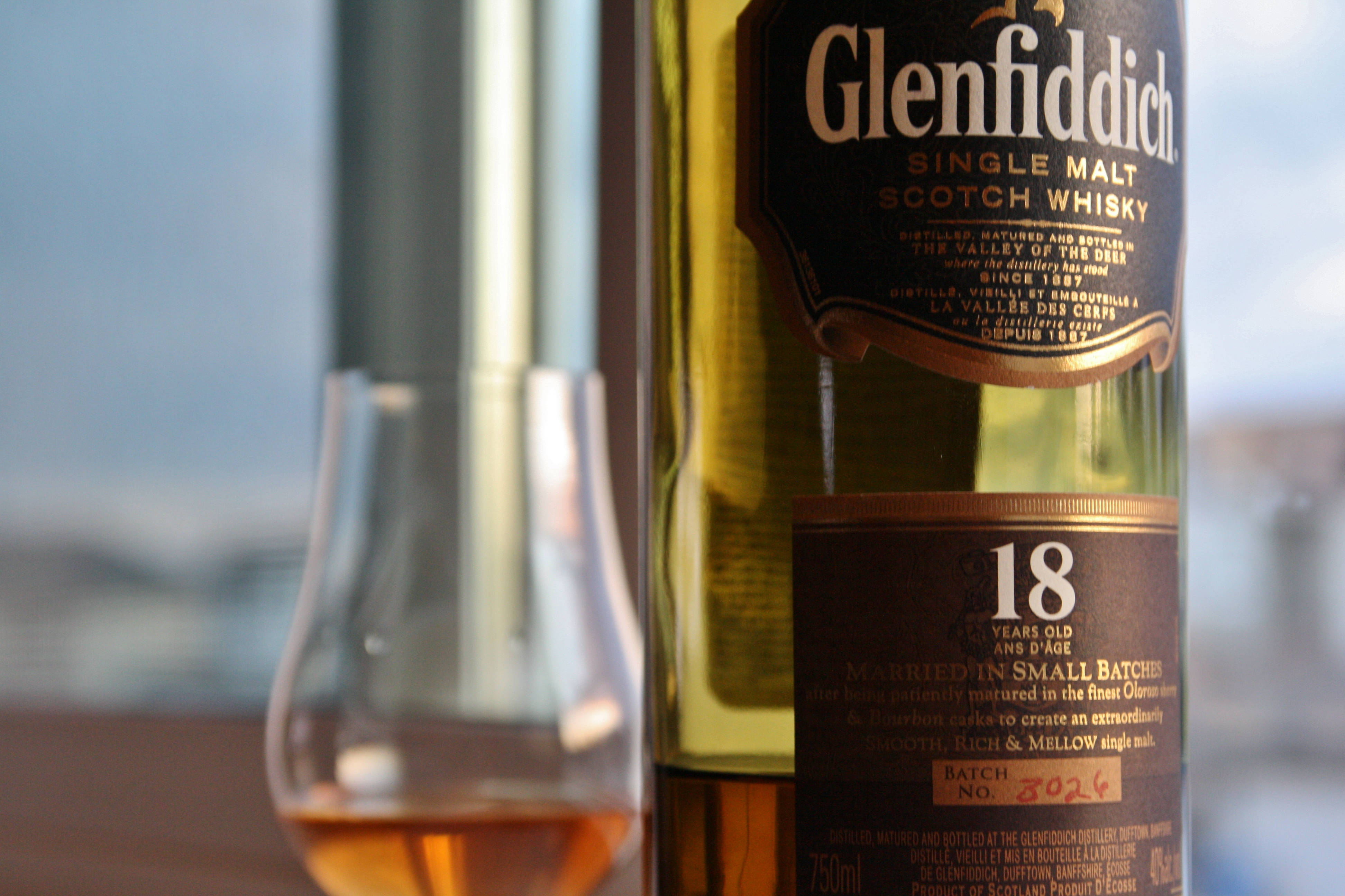 alcohol 桌布 壁紙 — Glenfiddich 18年單一麥芽威士忌酒瓶的特寫，旁邊放著一個裝滿琥珀色液體的品酒杯。