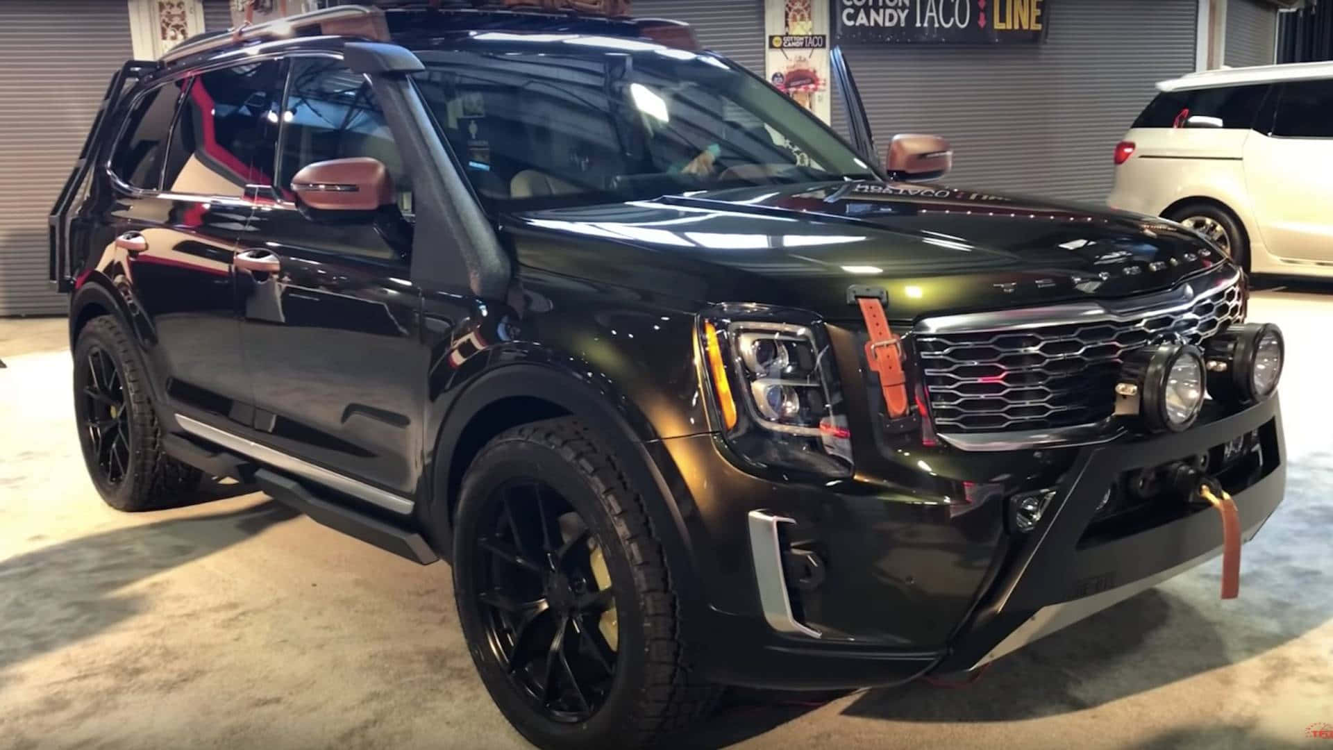 Kia Telluride 桌布 壁紙 — 一輛亮黑色福特Expedition SUV，配備客製化越野改裝，在明亮燈光下停放在室內。