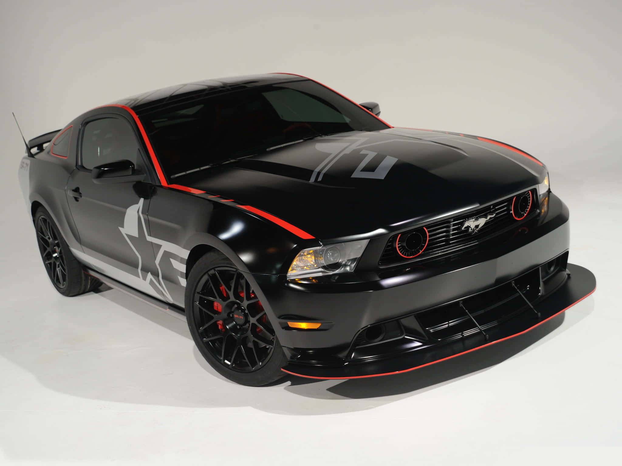Ford Mustang Roush 桌布 壁紙 — 一輛亮黑色福特野馬，帶有紅色點綴和白色星星貼紙，擺放在純白色工作室背景前。