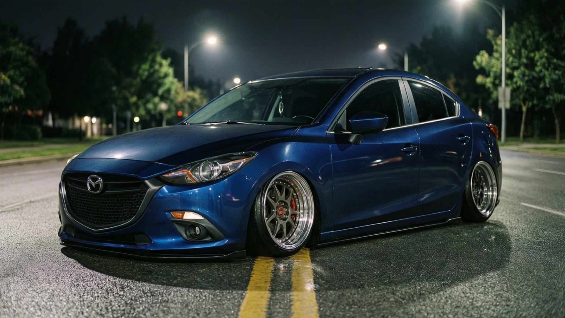 Night Custom 壁紙 — 一輛光澤藍色Mazda 3轎車配備定制輪圈，在夜間濕滑的街道上低趴於街燈下。