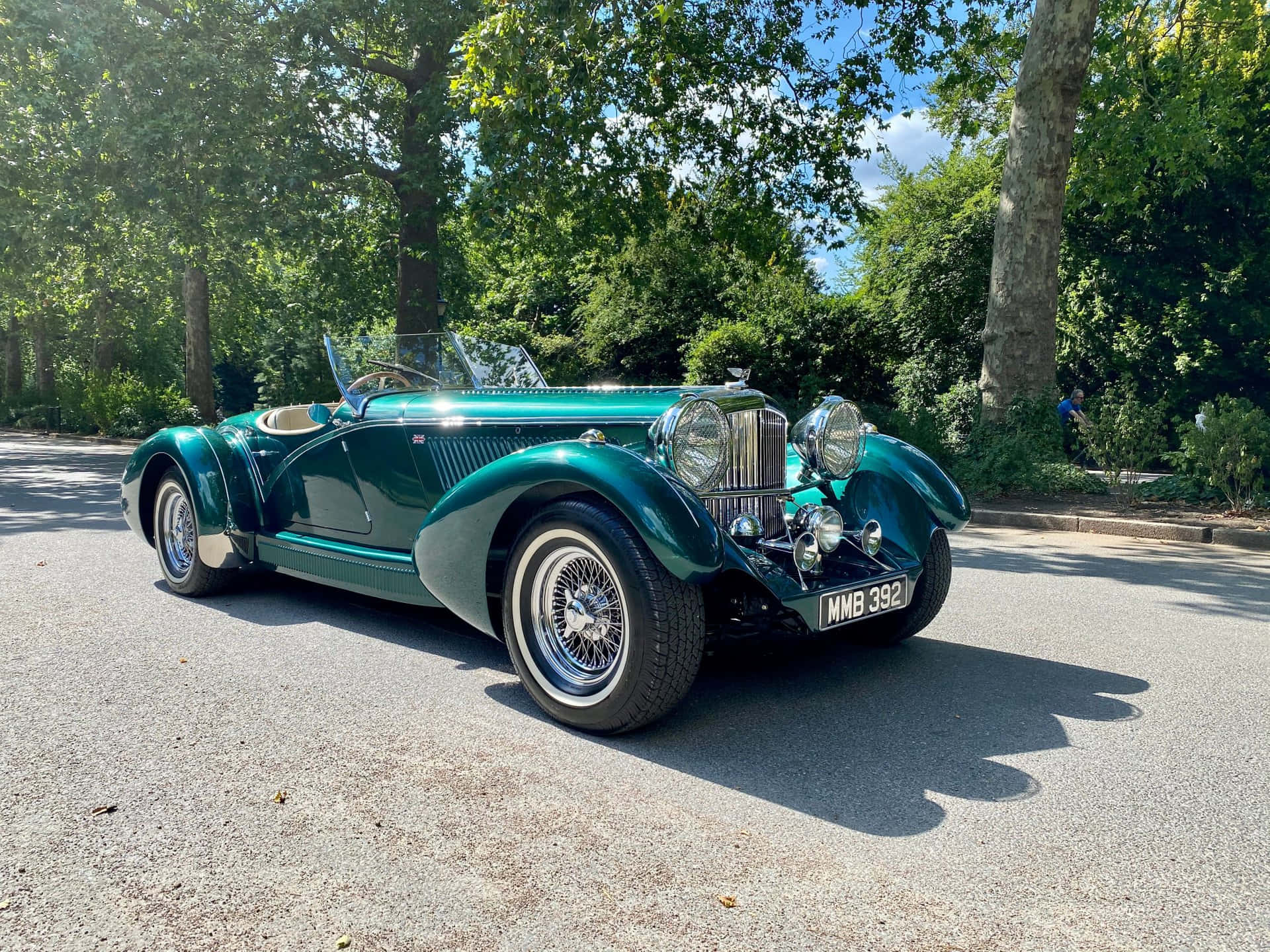 Bentley Mark Vi 桌布 壁紙 — 一輛閃亮的翠綠色經典敞篷跑車在陽光明媚的樹蔭大道上閃閃發光。