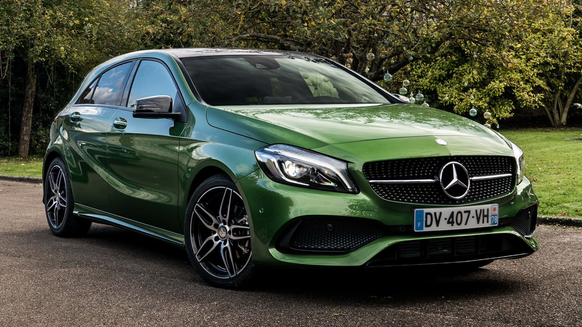 Mercedes Benz A-class 桌布 壁紙 — 一輛光澤的綠色賓士A-Class掀背車停在鋪砌的道路上，背景有樹木和草地。