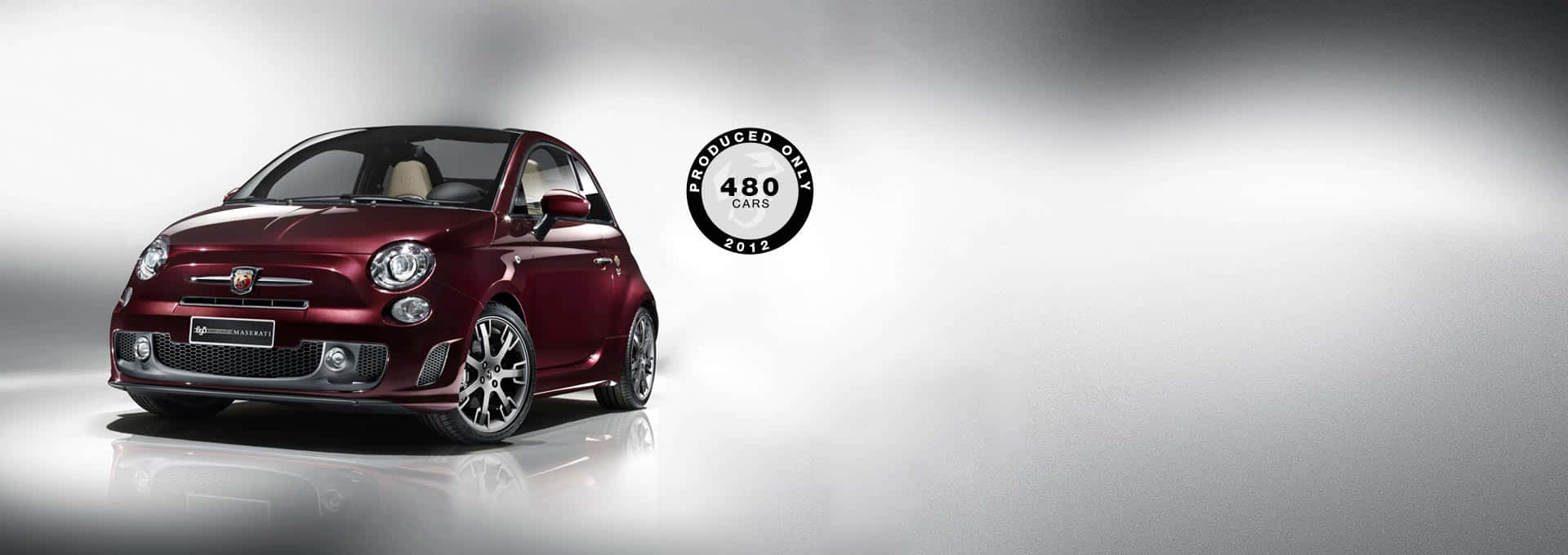 Fiat 500 桌布 壁紙 — 一輛光澤栗色的飛雅特500限量版汽車，2012年生產了480輛，在反射性工作室地板上以戲劇性燈光展示。