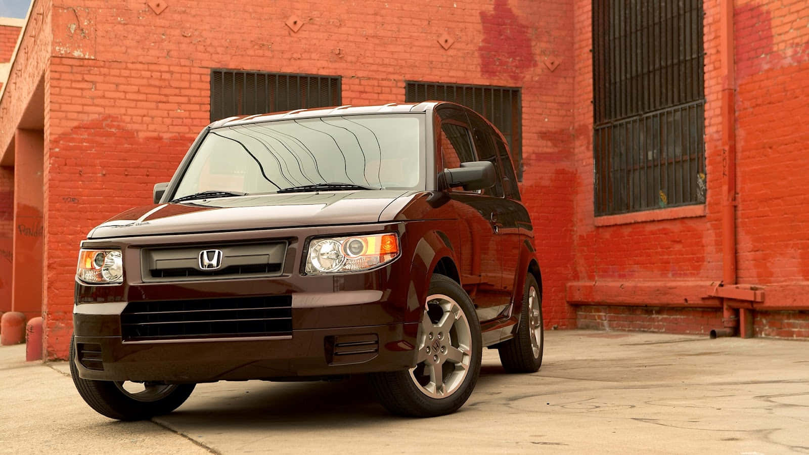 Honda Element 桌布 壁紙 — 一輛亮面栗色本田Element SUV停在一棟有鐵窗的風化紅磚建築前面。