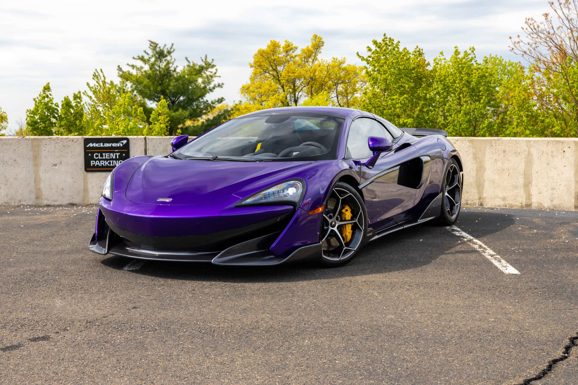 Mclaren 600lt Spider 桌布 壁紙 — 一輛光澤紫色McLaren跑車停放在客戶停車場，背景有綠色樹木。