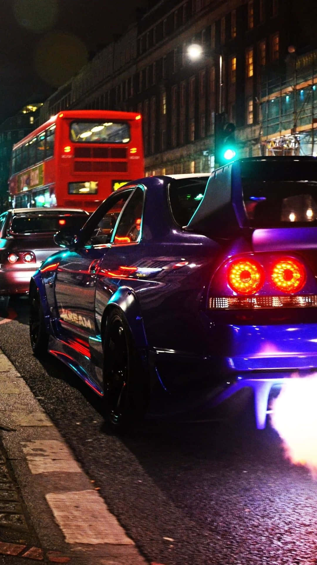 紫色跑車帶著發光的燈光在夜間雨中的城市街道上飛馳。 — R33 GT-R 壁紙
