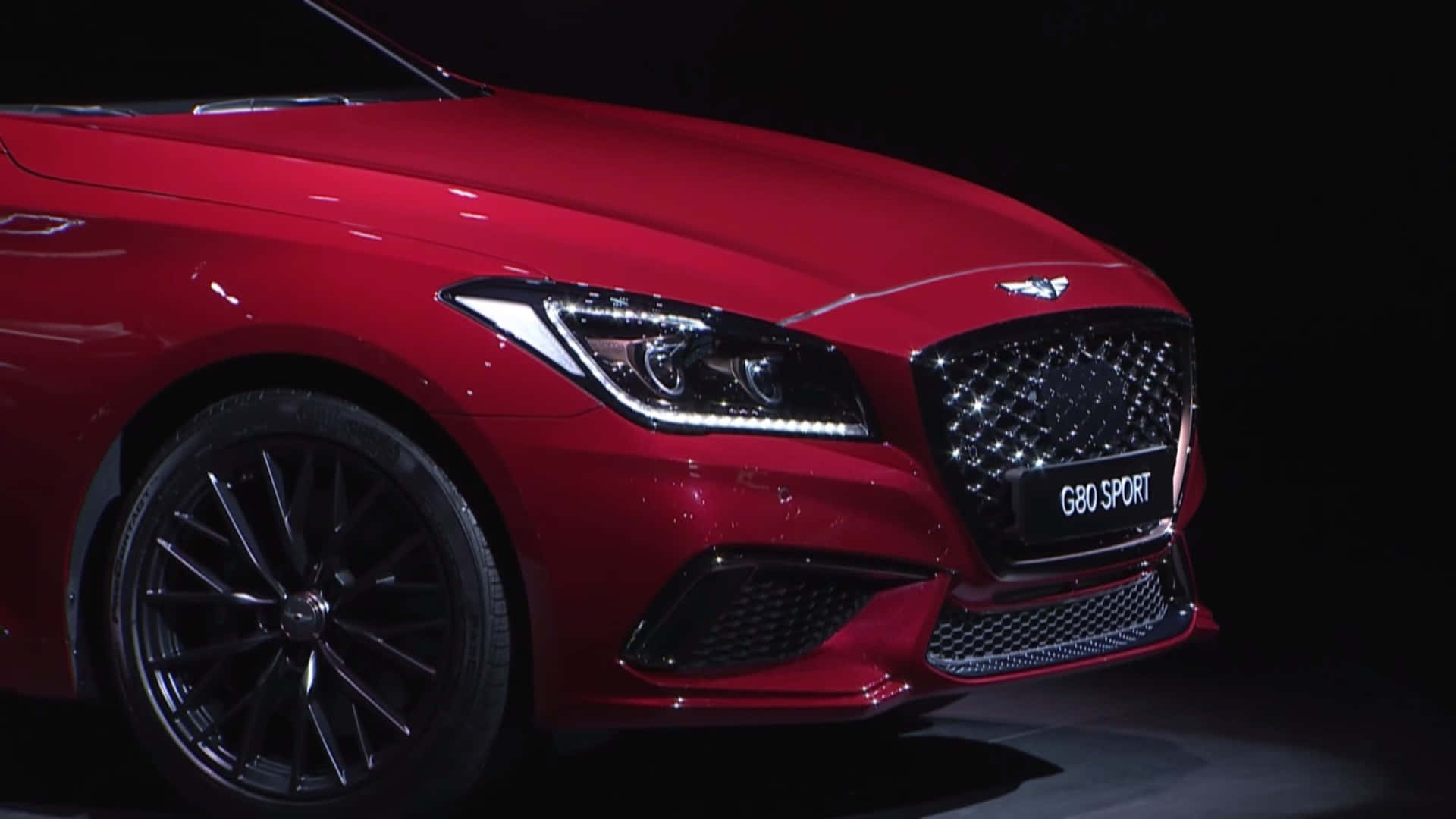 Genesis G80 桌布 壁紙 — 一輛亮紅色的賓利 Continental G80 Sport 在黑色背景下，於戲劇性的舞台燈光下閃閃發光。