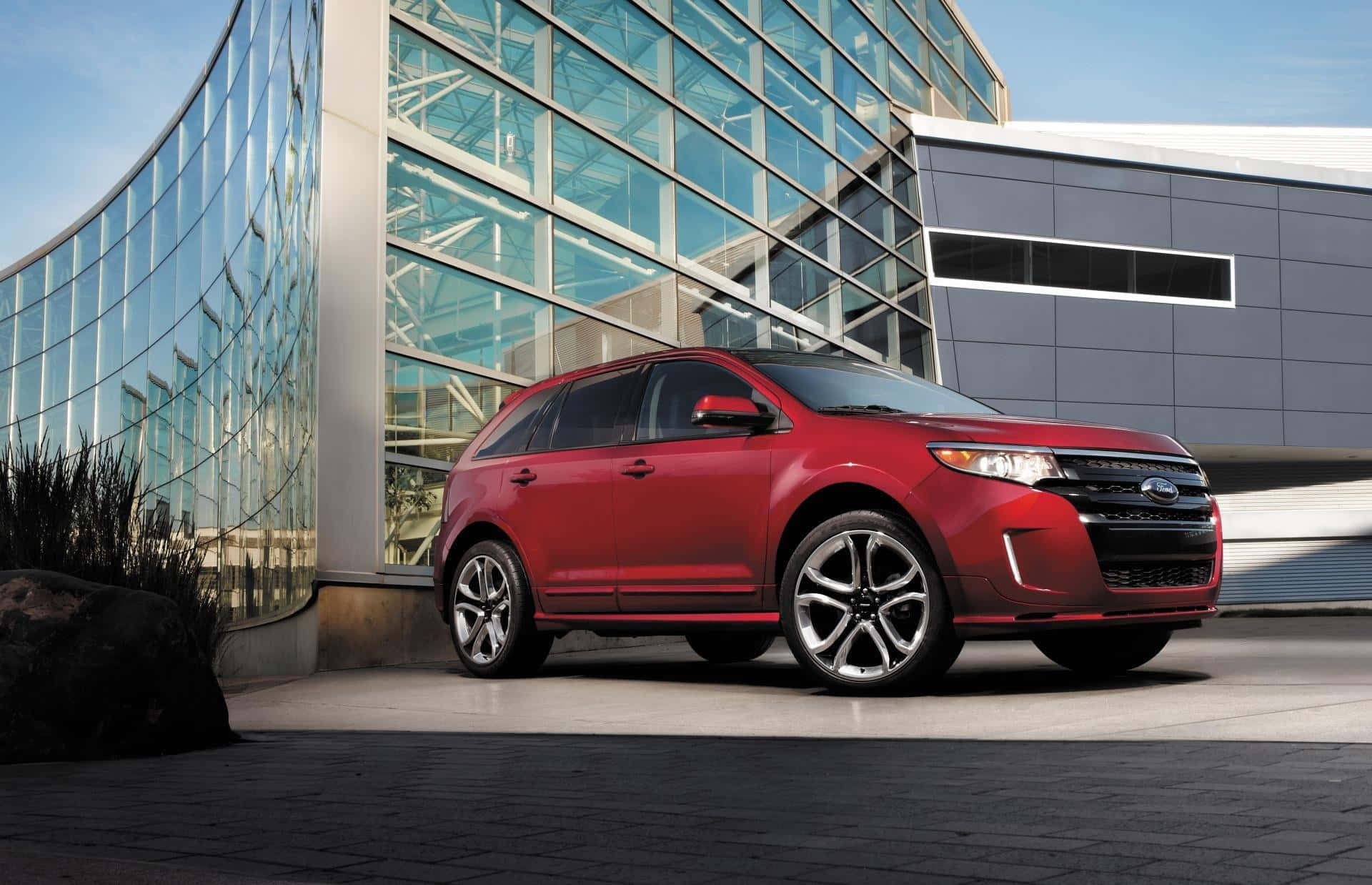 Ford Edge 桌布 壁紙 — 一輛亮紅色的福特Edge SUV停在一棟現代玻璃和鋼結構建築前，天空清澈湛藍。