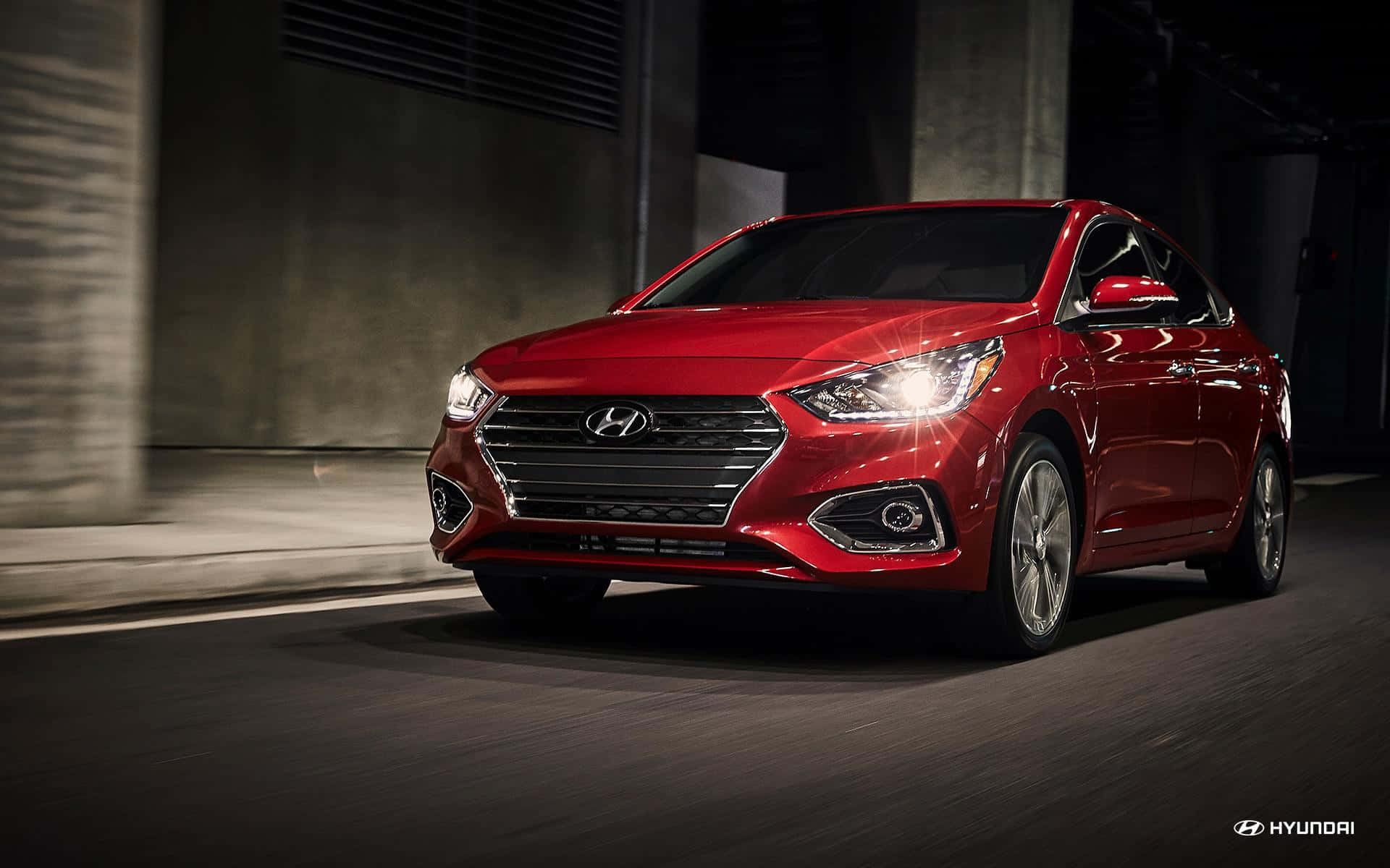 Hyundai Accent 桌布 壁紙 — 一輛亮紅色現代轎車在昏暗的城市隧道中疾馳，瀝青路面上帶有動態模糊效果。