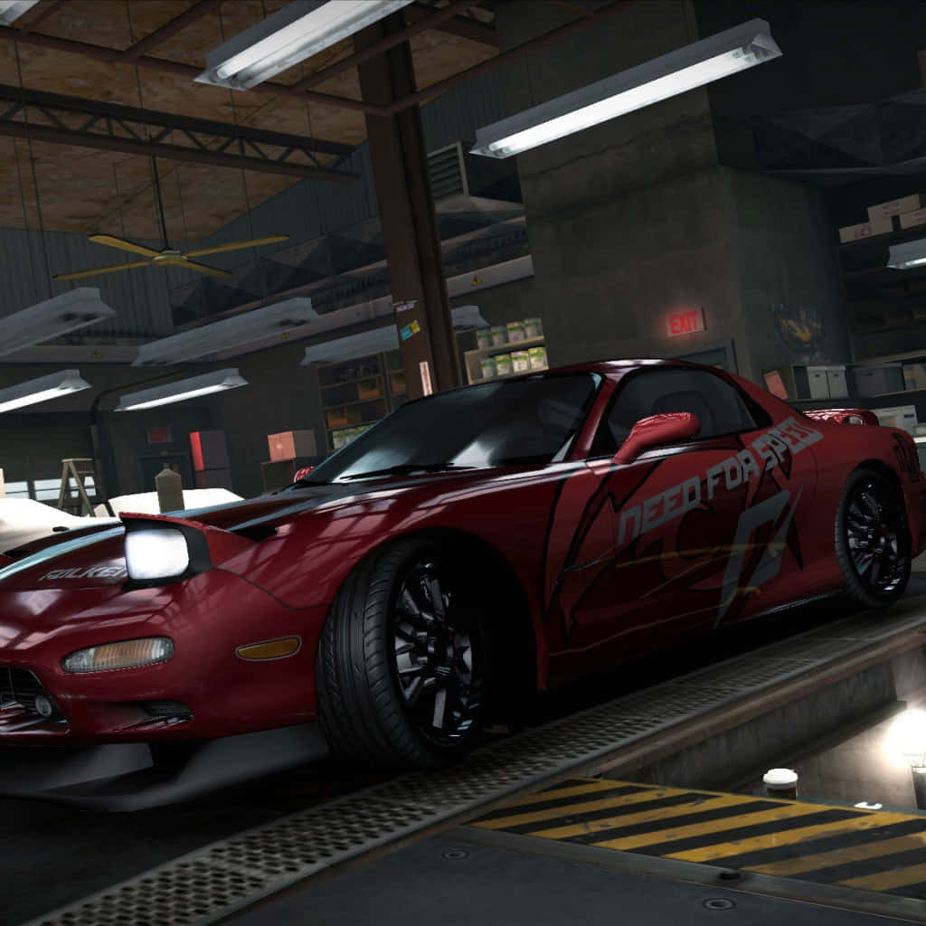  壁紙 — 一輛光澤的紅色馬自達RX-7帶有'Need for Speed'貼紙，停在車庫升降台上，下方是螢光燈。