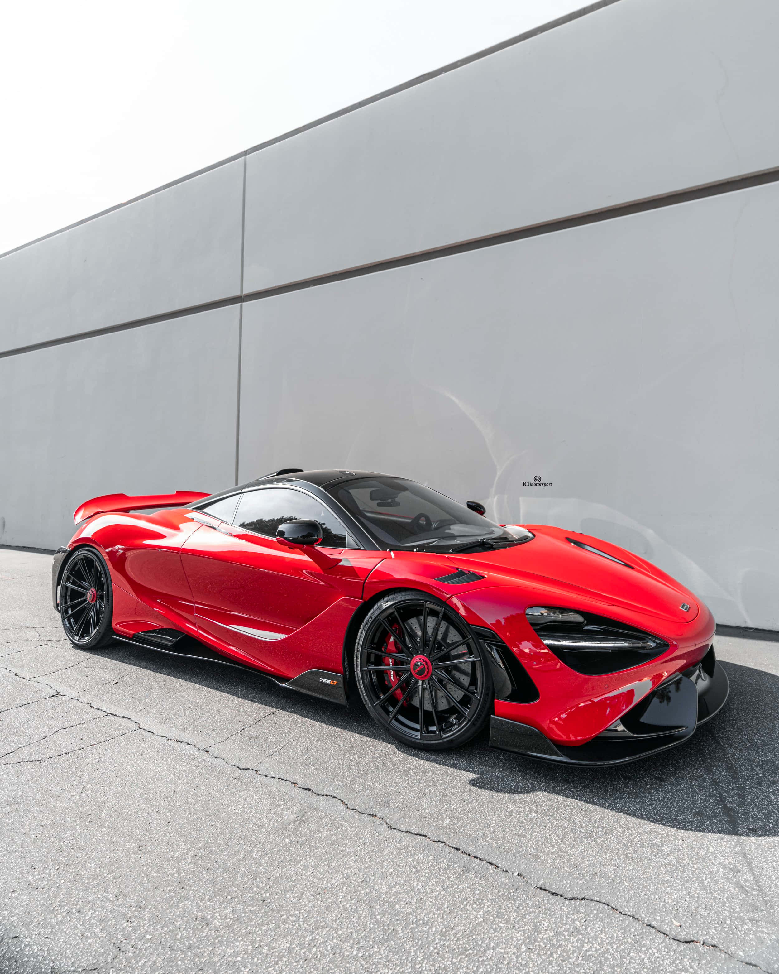 Mclaren 765lt 桌布 壁紙 — 一輛亮紅色McLaren Senna跑車在明亮日光下停泊在簡約灰色牆前。