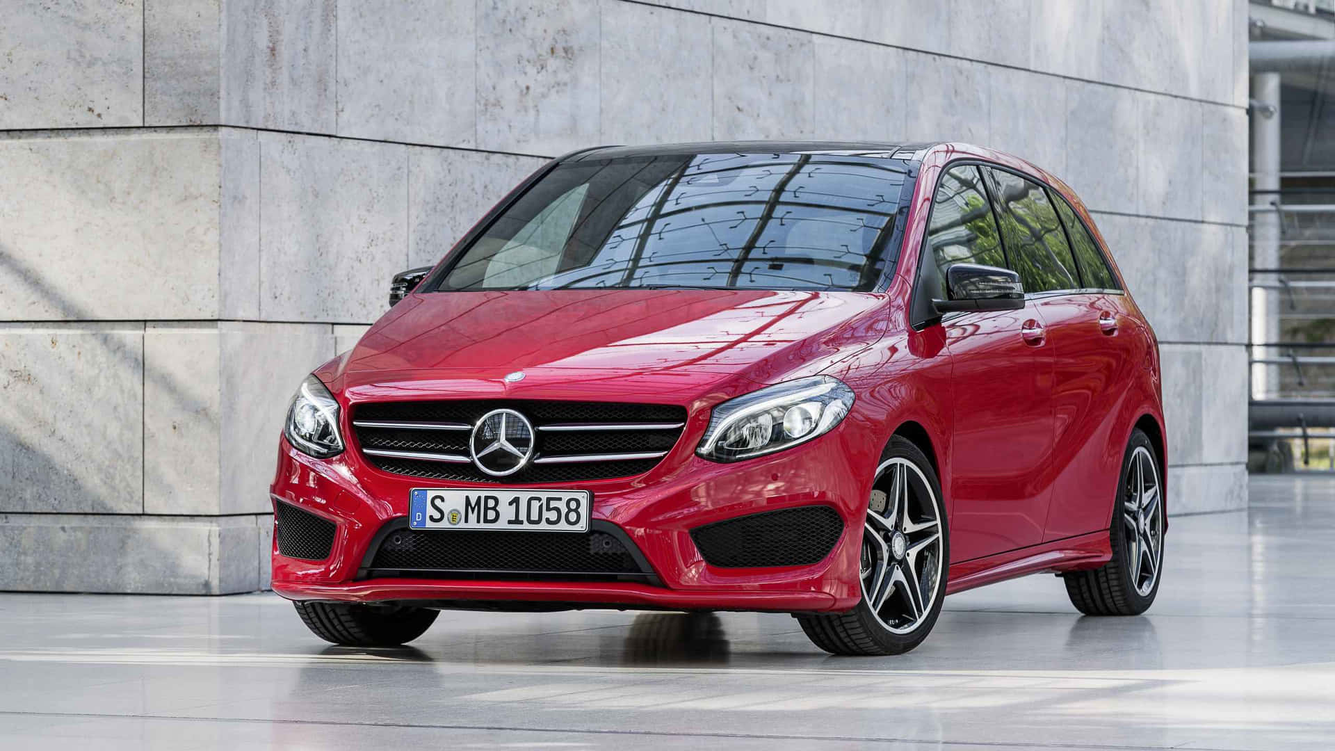 Mercedes Benz B-class 桌布 壁紙 — 一輛亮紅色的梅賽德斯-奔馳B級車停在現代混凝土牆旁，陽光投下銳利的陰影。