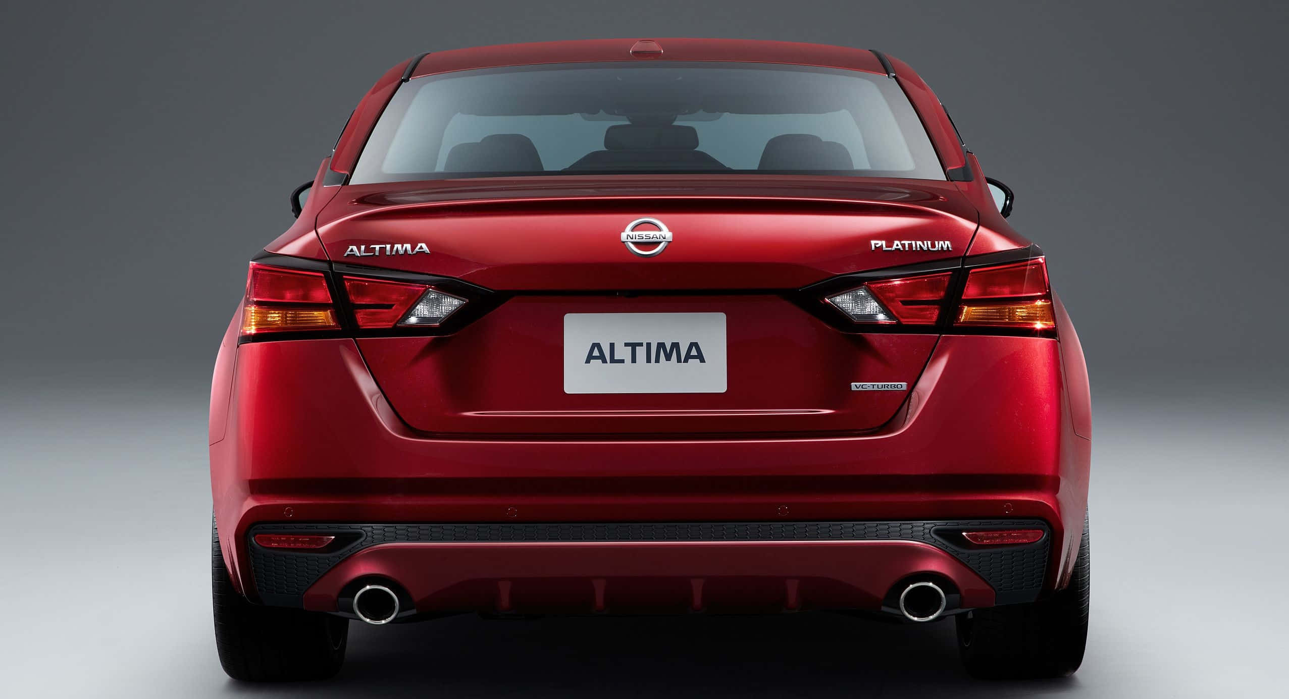 Nissan Altima 桌布 壁紙 — 一輛亮紅色日產Altima Platinum轎車從後方觀看，背景為中性灰色攝影棚。