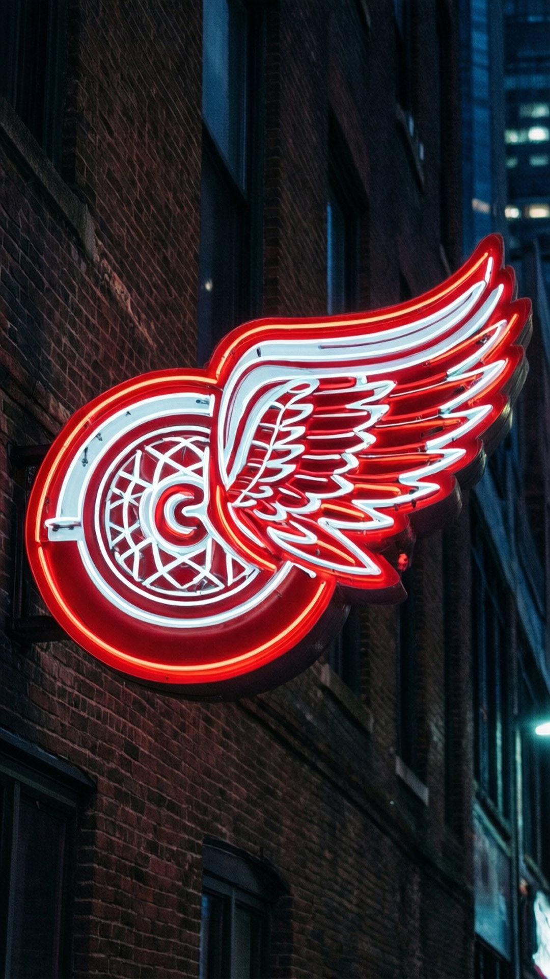 Neon Wings Sign 壁紙 — 夜間安裝在磚砌建築物上的發光紅白霓虹燈標誌，帶有翼輪標誌。