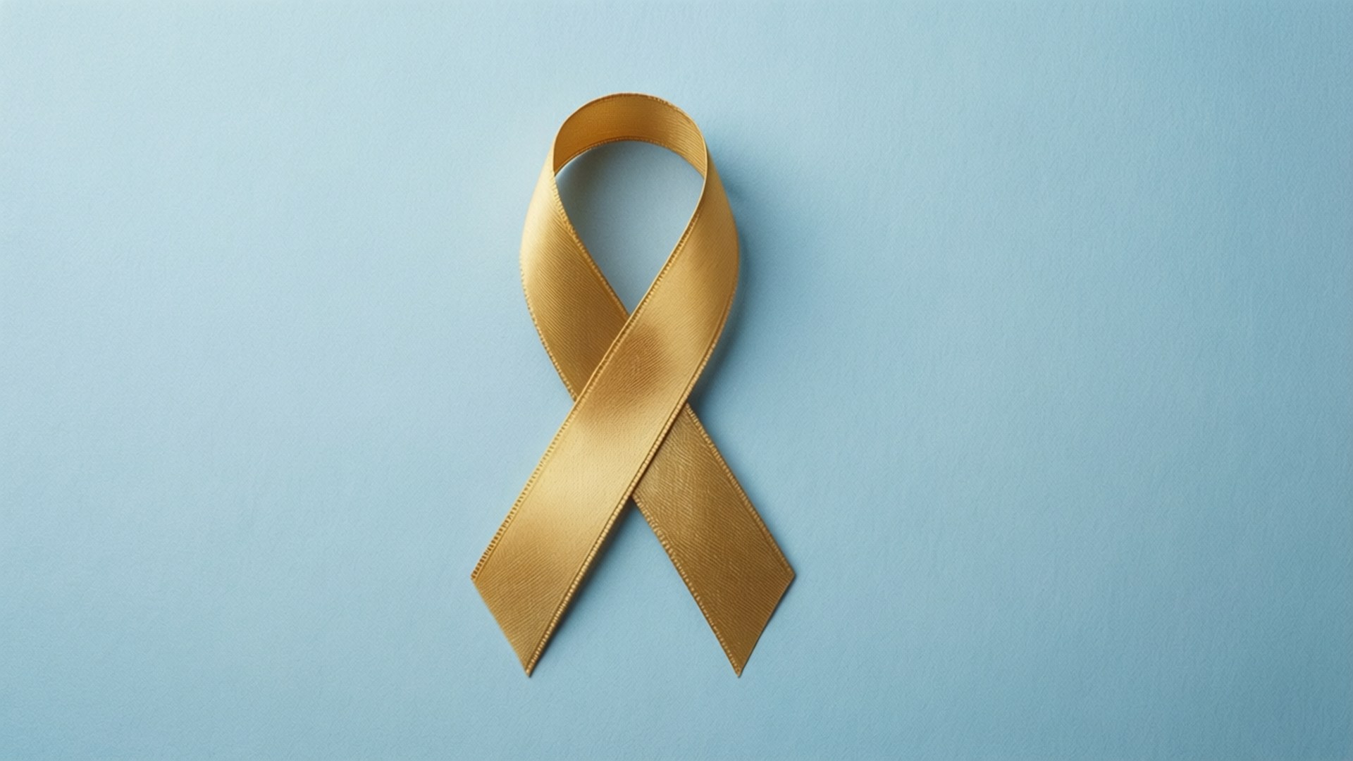 Childhood Cancer Awareness 桌布 壁紙 — 一條金色的意識絲帶居中放置在柔和的藍色背景上，帶有乾淨的光線和微妙的陰影。