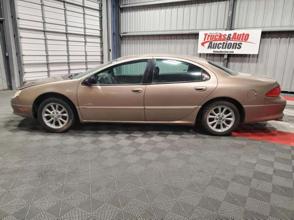Chrysler Lhs 桌布 壁紙 — 一輛金色轎車停放在金屬牆壁的汽車拍賣車庫內的棋盤格地板上。