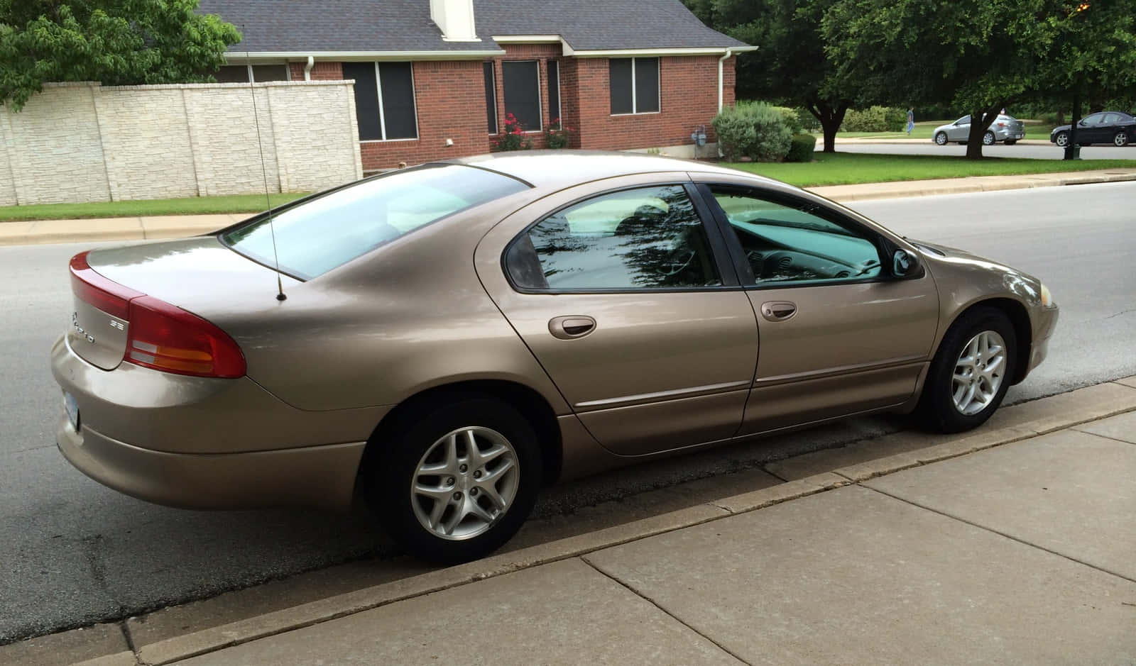 Dodge Intrepid 桌布 壁紙 — 一輛金色轎車停放在住宅街道旁的人行道上，背景有房屋和樹木。