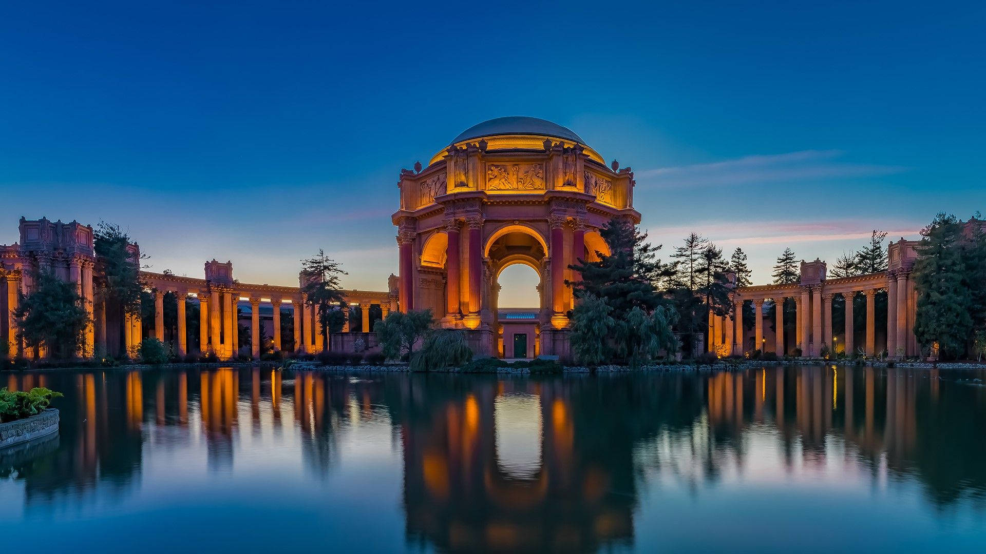 藝術 桌布 壁紙 — Golden Palace of Fine Arts 在黃昏時溫暖地發光，其宏偉的拱門和圓頂完美地倒映在周圍潟湖平靜的水面上。