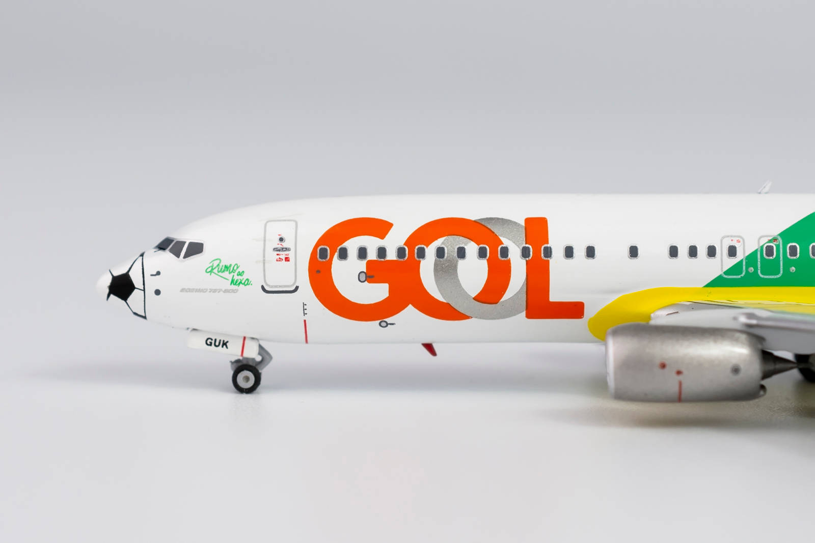 飛機 桌布 壁紙 — GOL航空公司波音737的詳細模型，帶有橙色、綠色和黃色塗裝，置於純白色背景上。