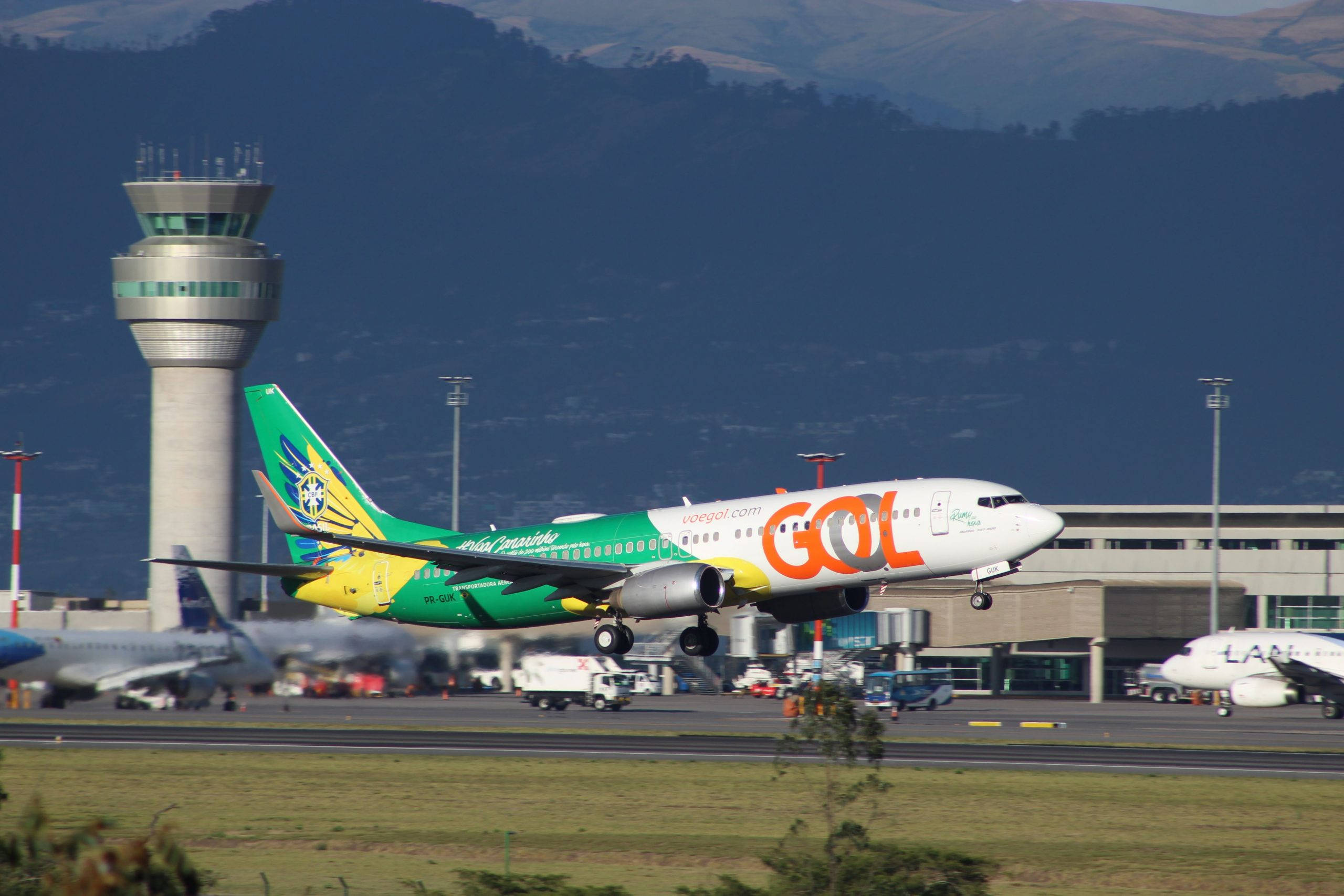 飛機 桌布 壁紙 — GOL航空的飛機從機場跑道起飛，背景有控制塔和山脈。