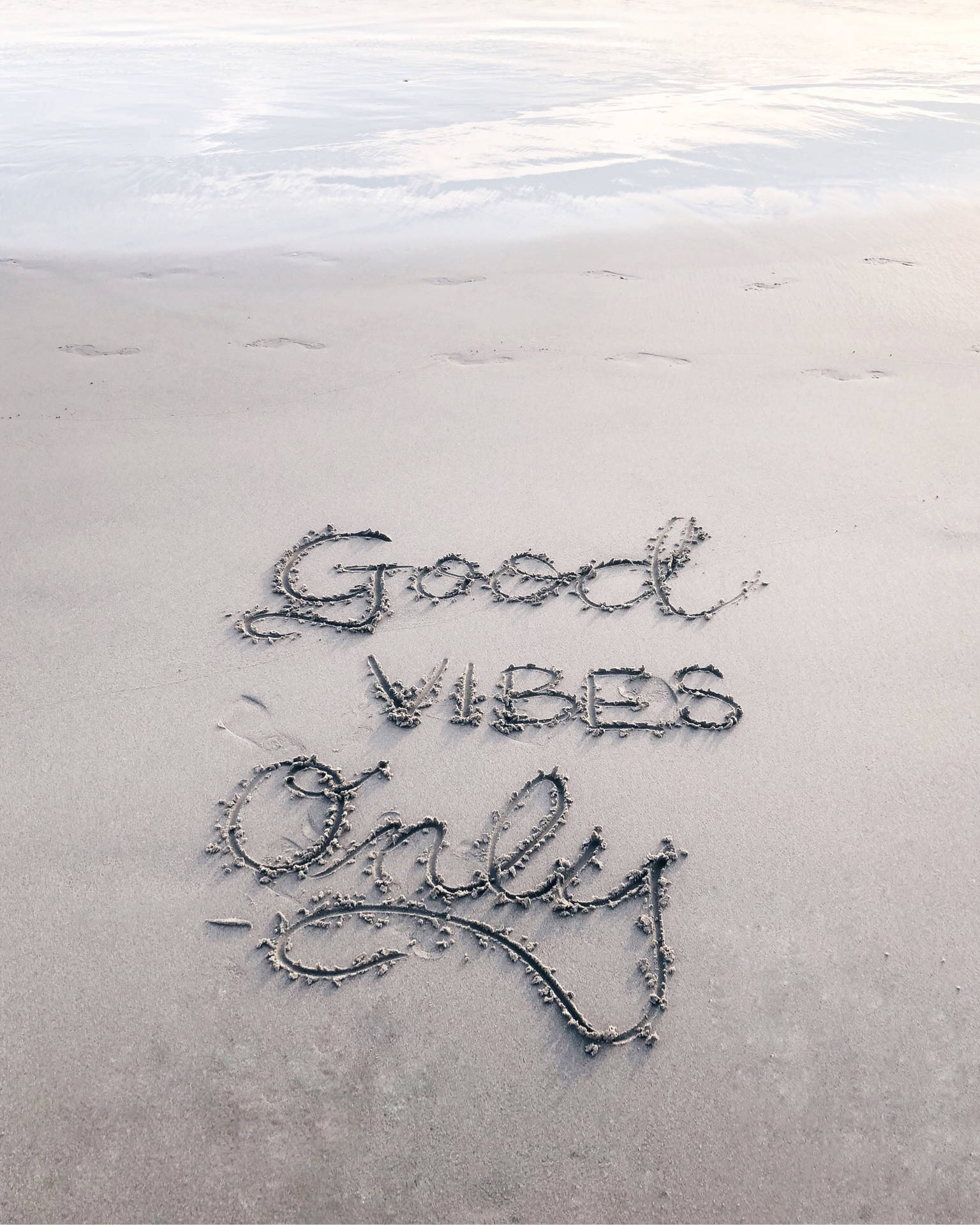 在海岸線的沙上寫著Good Vibes Only，伴隨著海浪。 — 激勵 壁紙